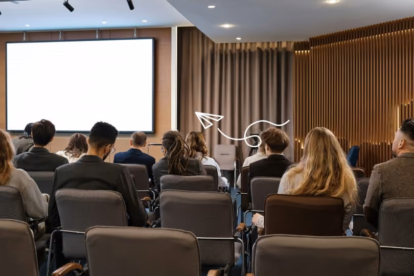 Konferensrum där många personer sitter och ser mot en scen med en presentation