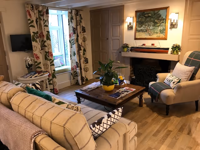 Cozy living room with floral curtains, fireplace, and comfortable furniture