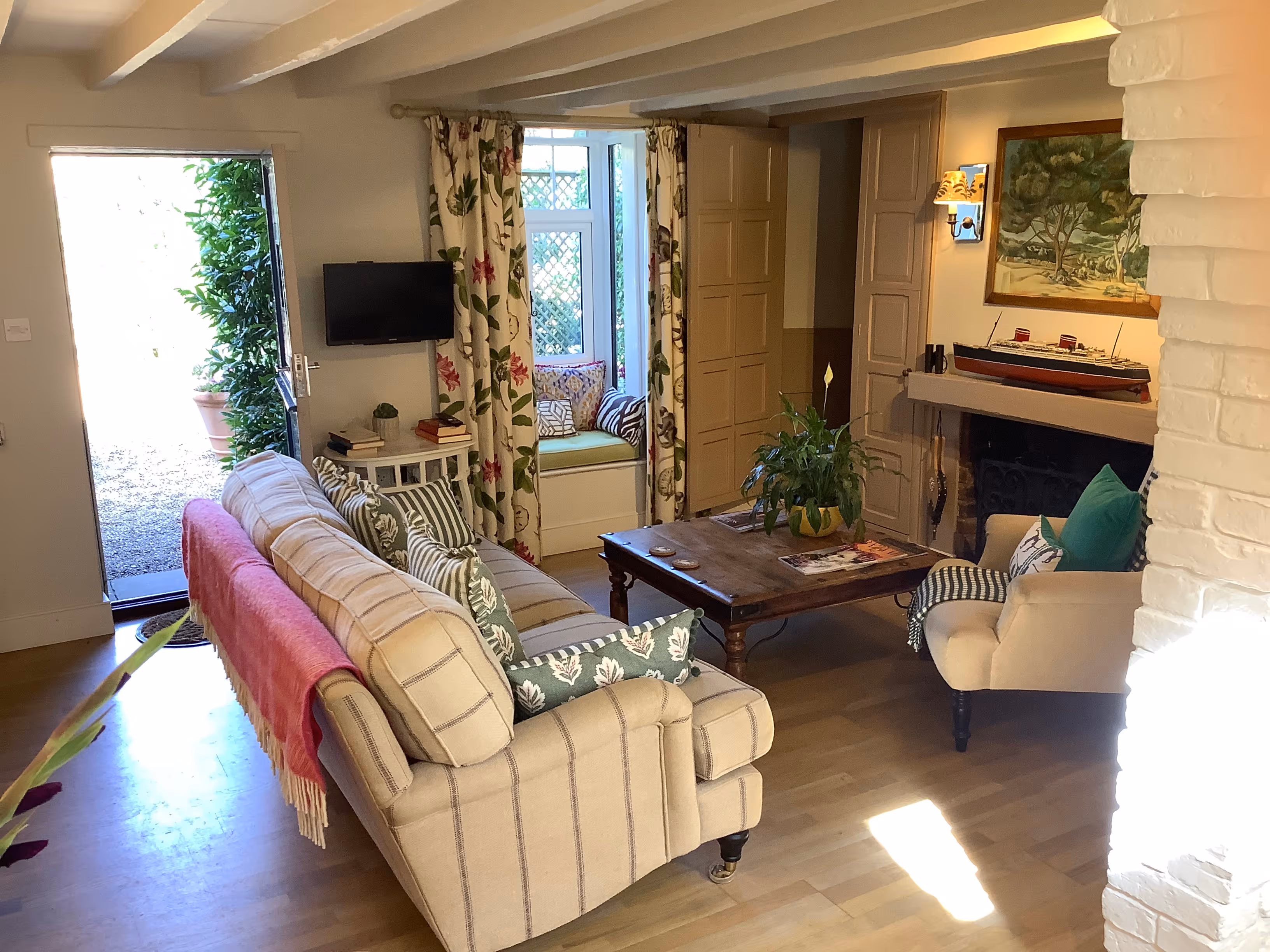 Cozy living room with striped furniture, floral curtains, and window seat