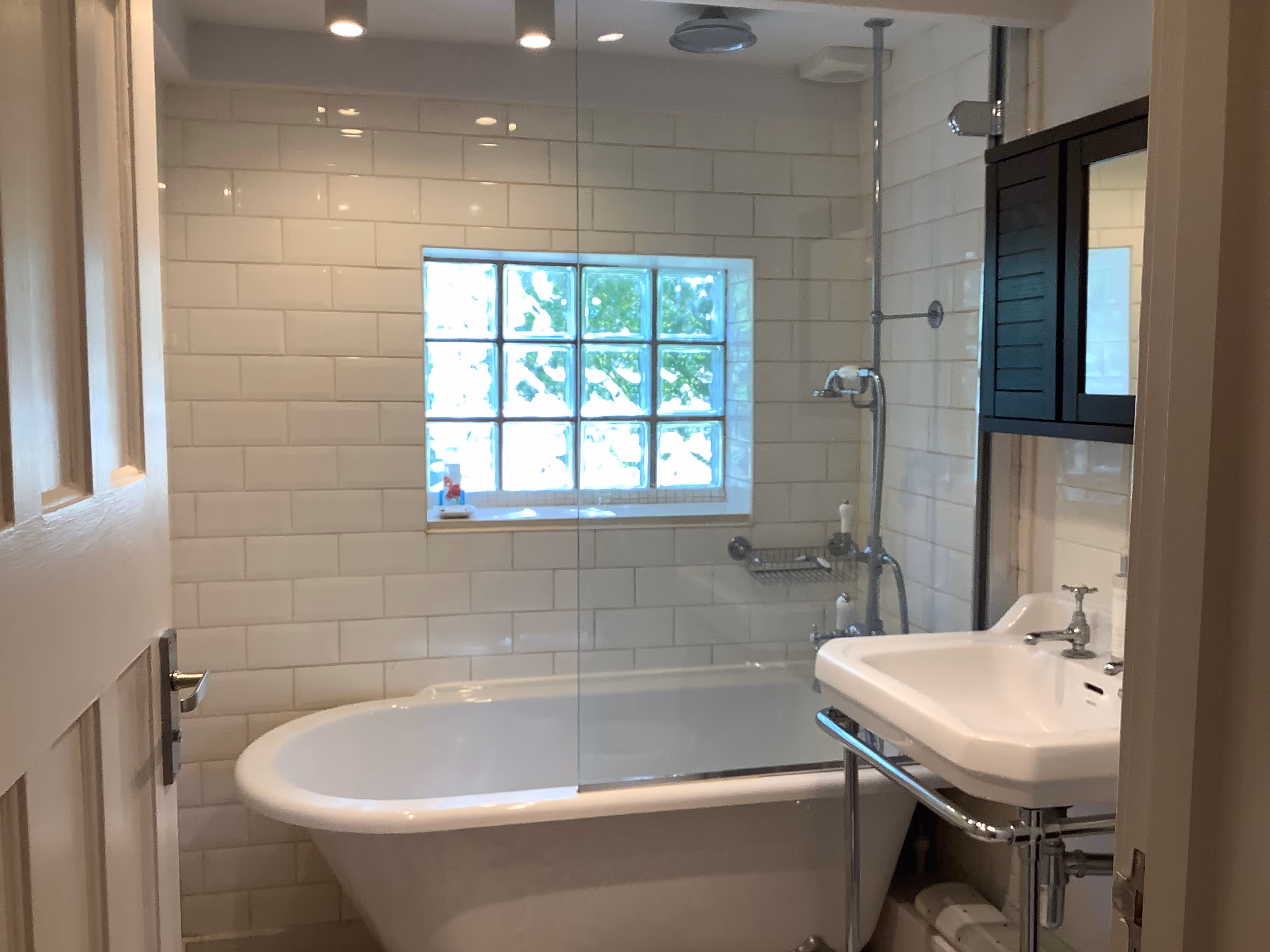 Modern bathroom with white subway tiles, freestanding tub, and natural light