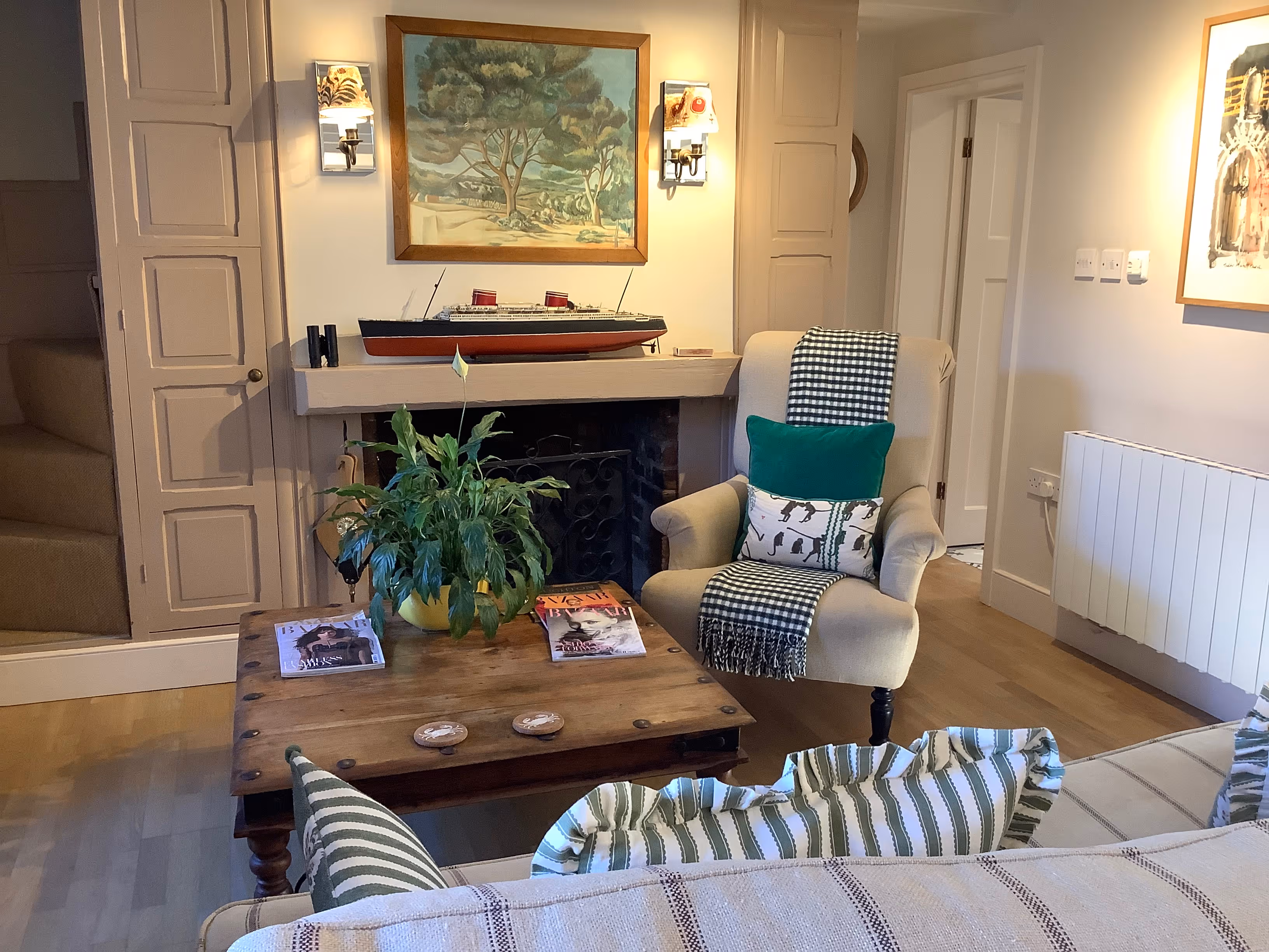 Cozy living room with fireplace, ship model, art, and comfortable seating