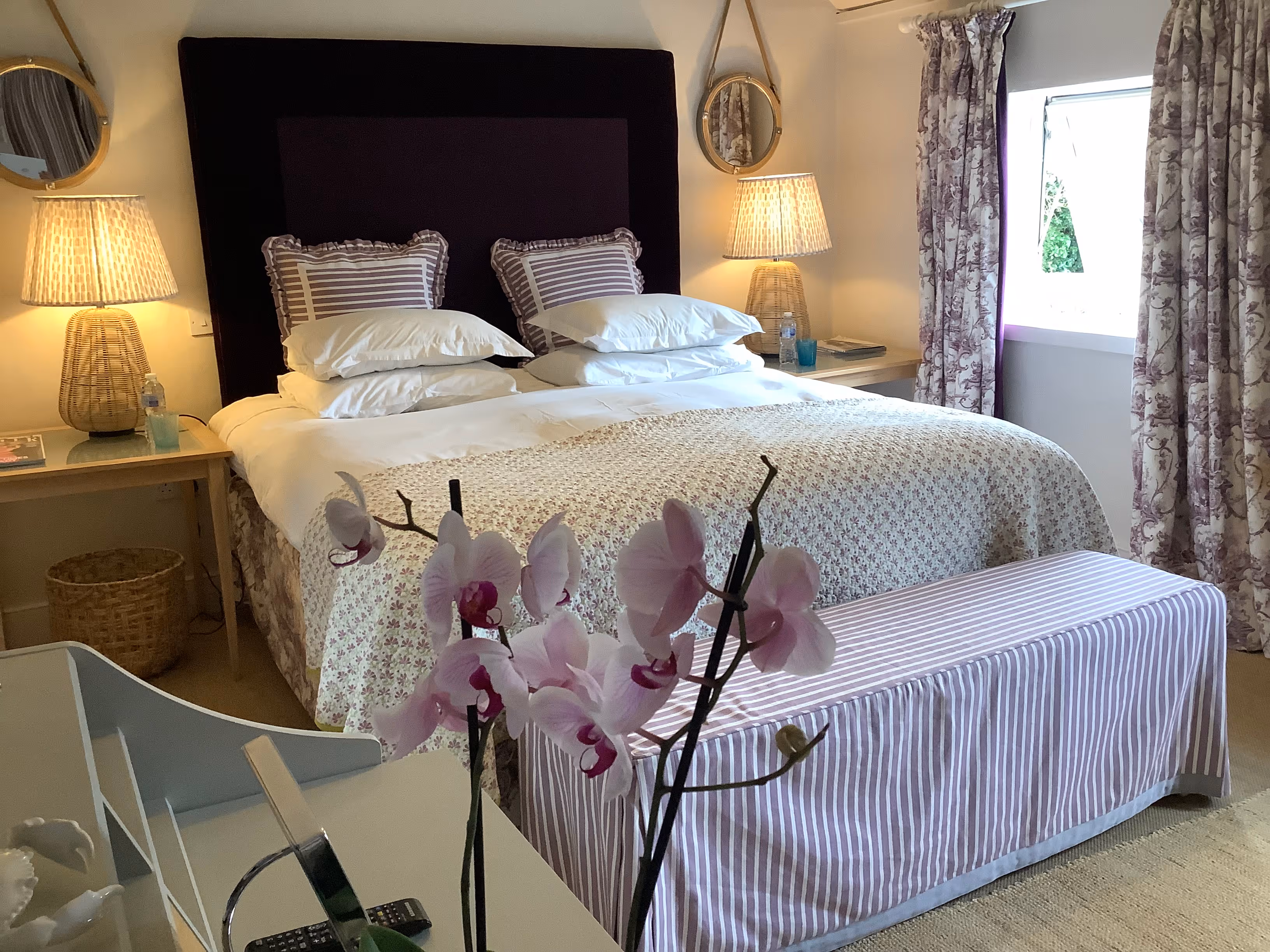 Cozy bedroom with white bedding, orchids, and warm lamp lighting