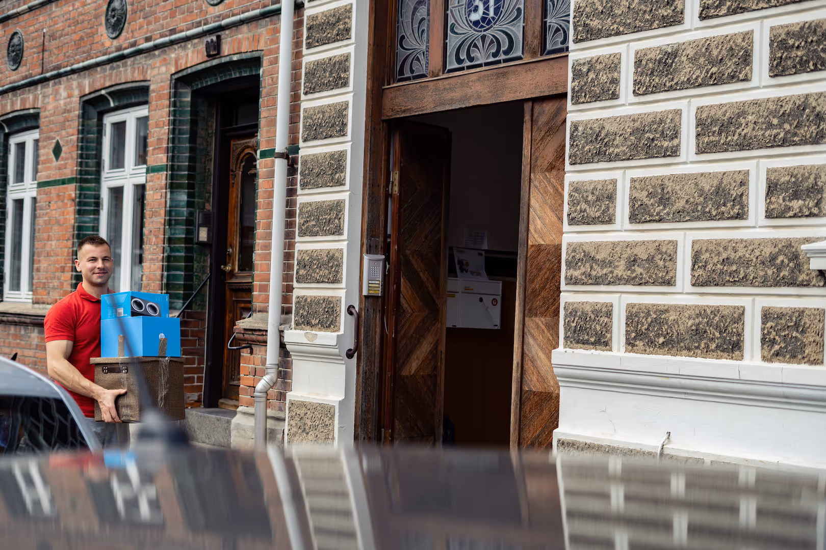 Paul carrying blue moving box into home in Horsens, Denmark