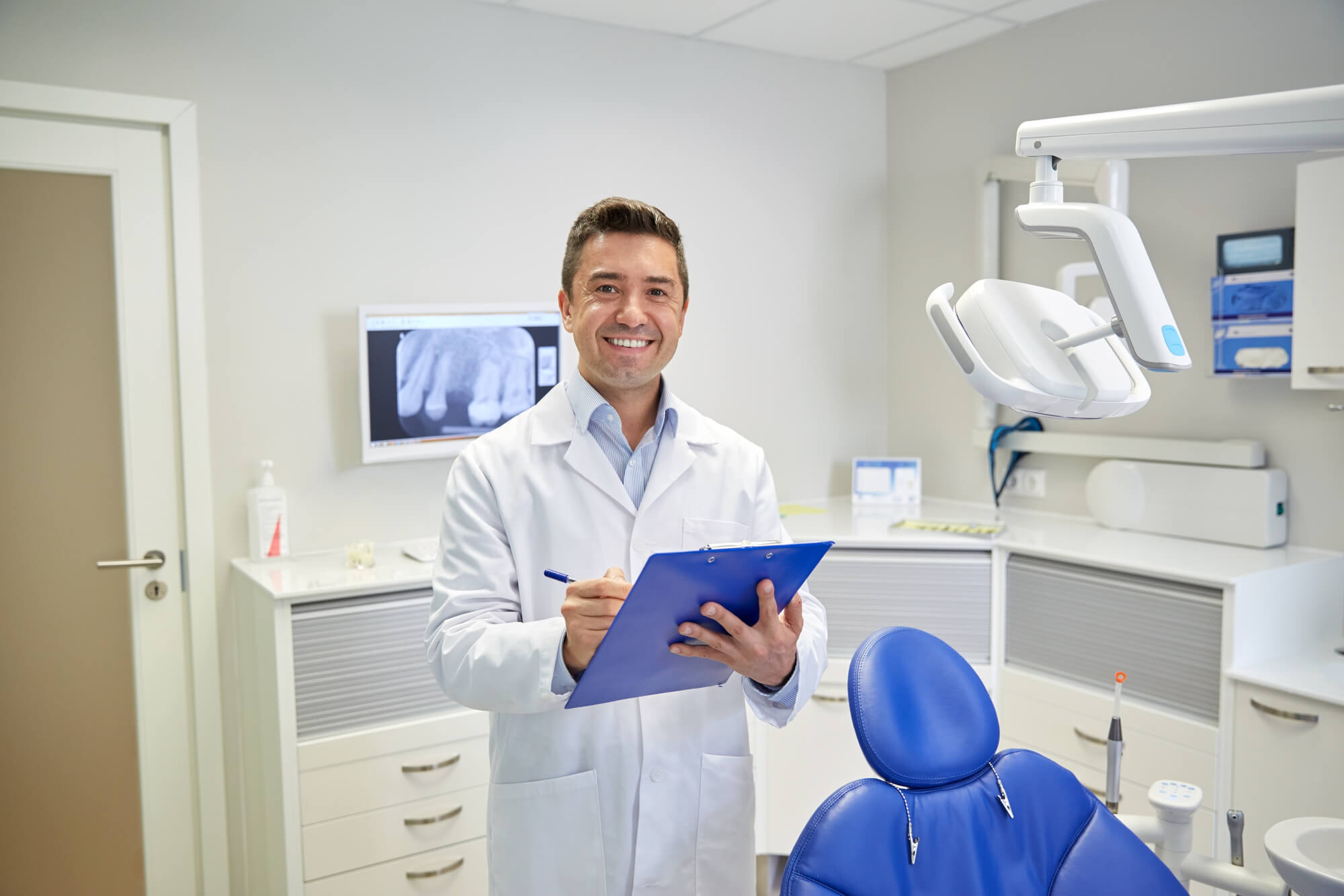 happy dentist writing on clipboard