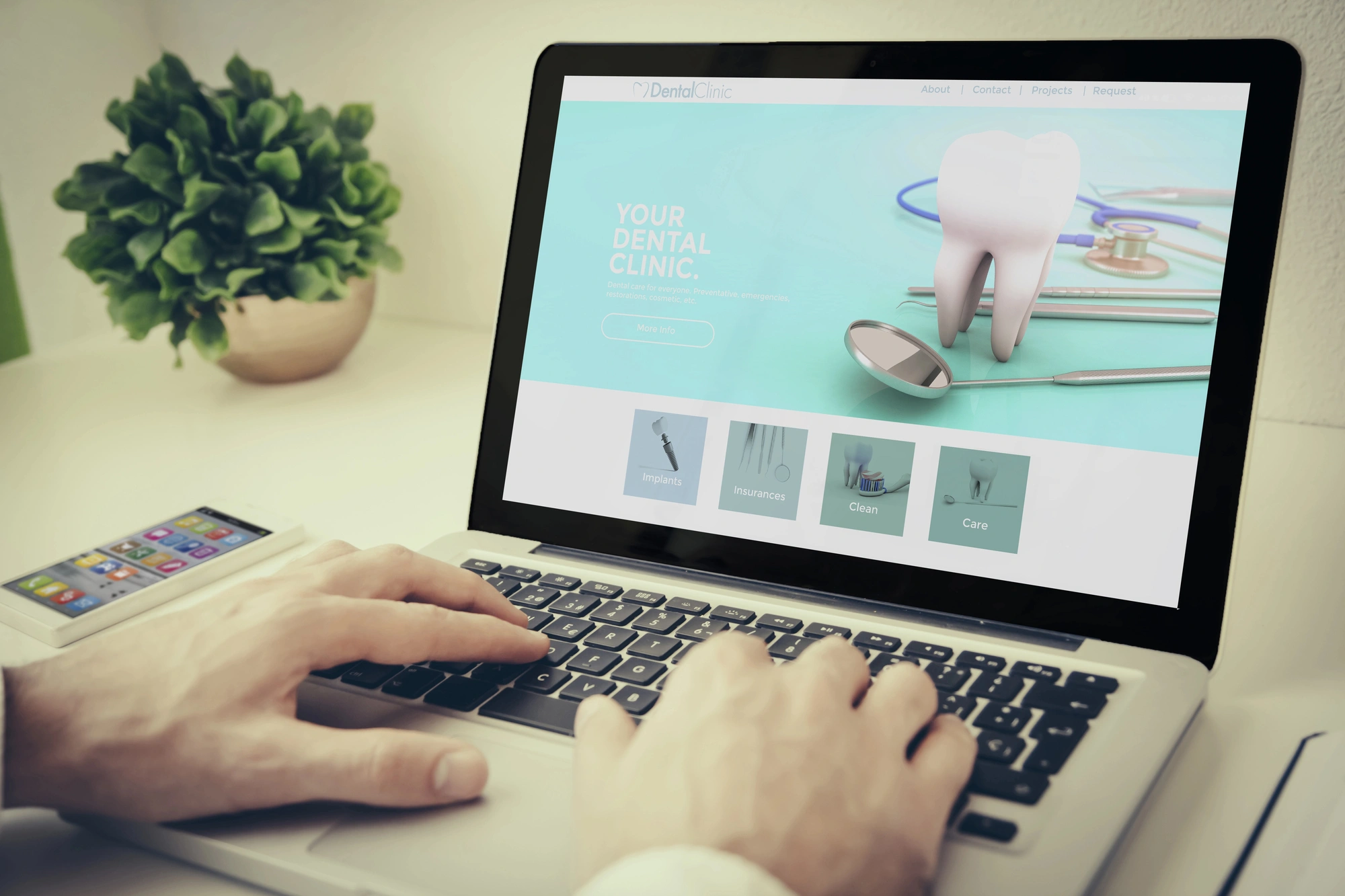 Person browsing a dental clinic website on a laptop with dental tools and a tooth image displayed on screen