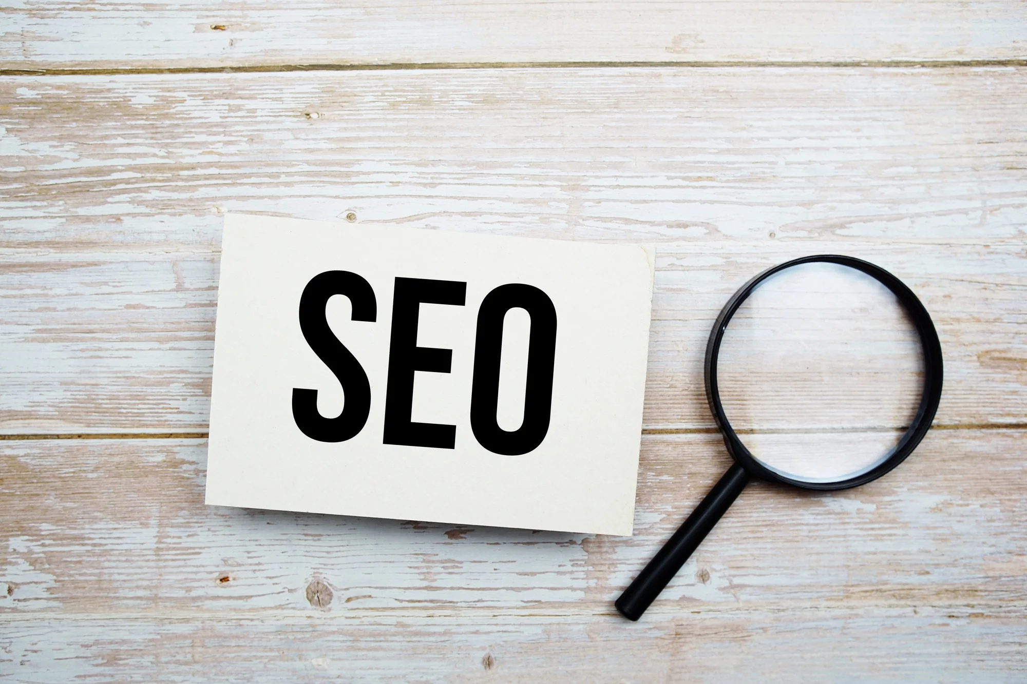Magnifying glass over paper with 'SEO' written, concept of franchise SEO optimization