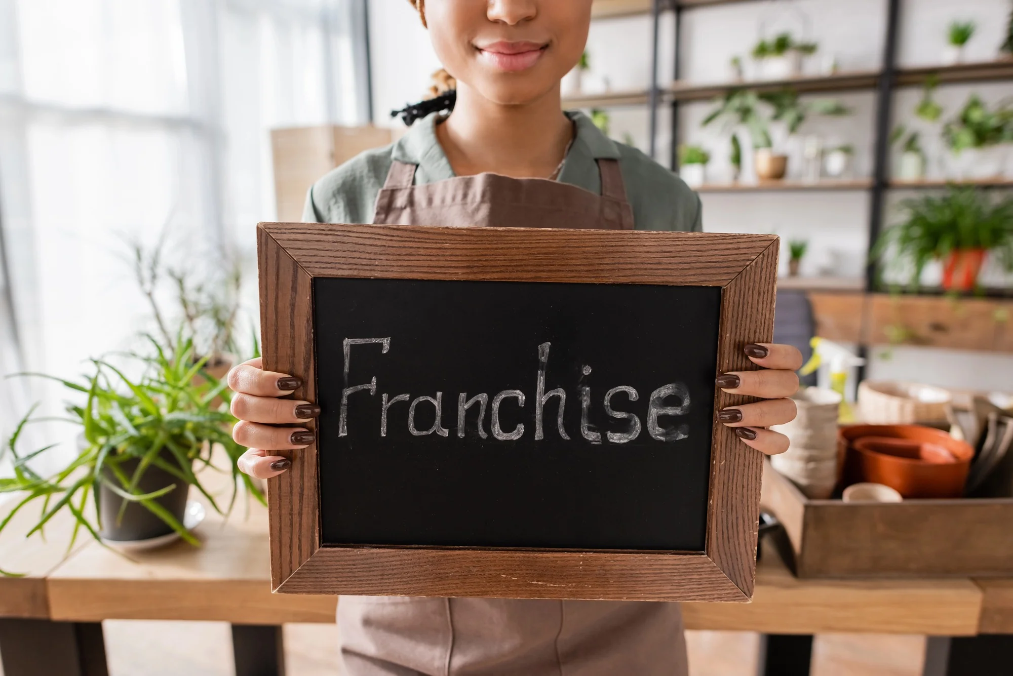 Cafe worker holding a chalkboard sign displaying the word 'Franchise'