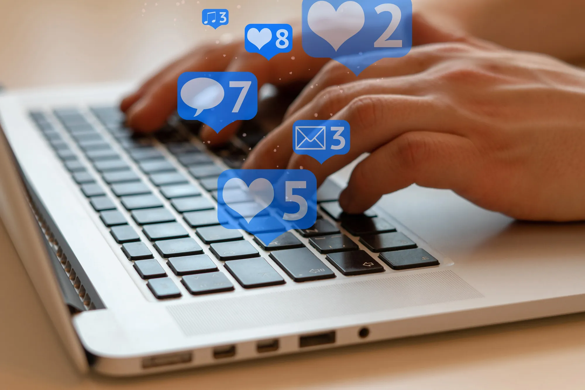 Hands typing on a laptop keyboard with social media notification icons for likes, comments, and messages overlaid