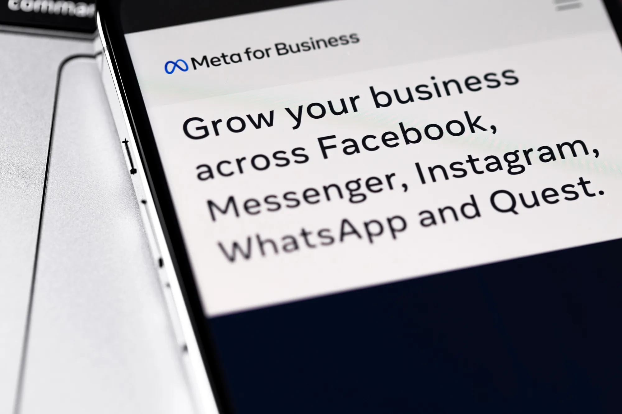 Close-up of a smartphone screen displaying the Meta for Business grow-your-business message next to a laptop