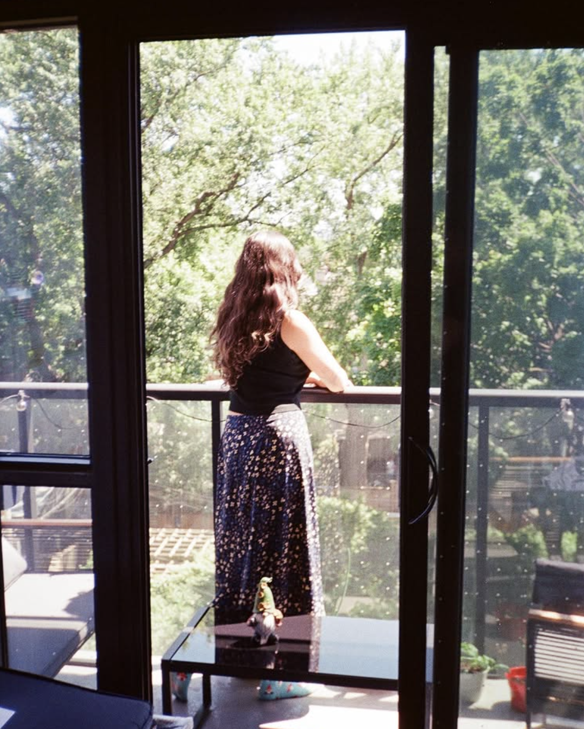 Nicole looking out from a balcony window at trees