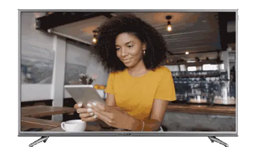 Woman in yellow shirt using a tablet sitting at a café table with a coffee cup.