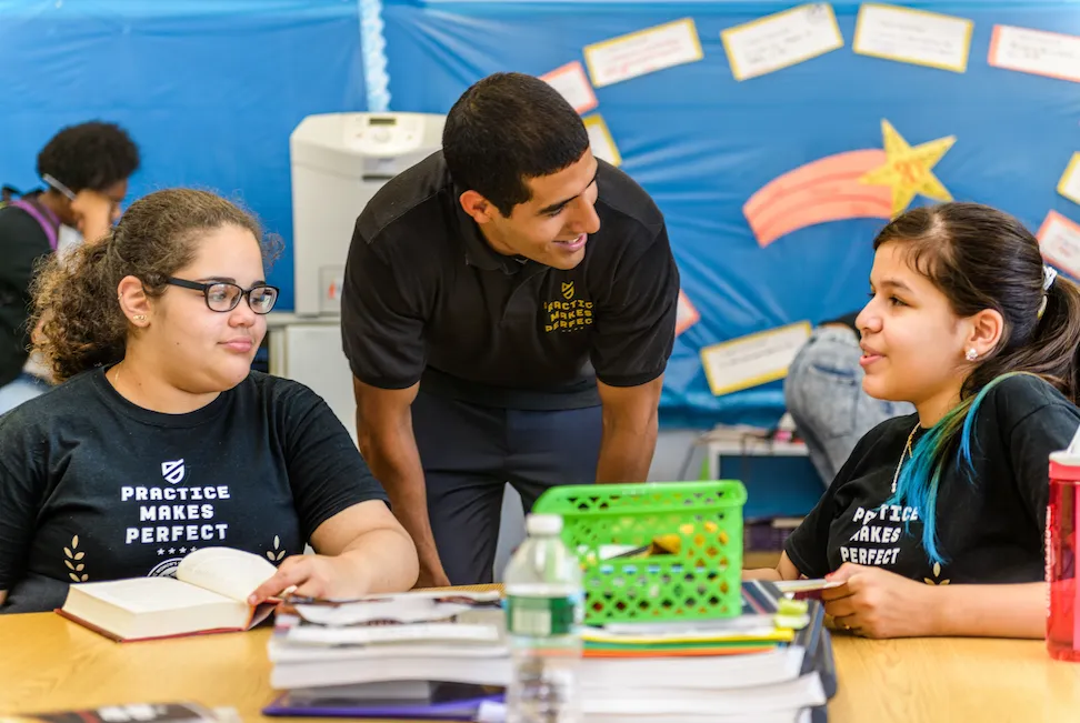 A man tutoring young students in a classroom 