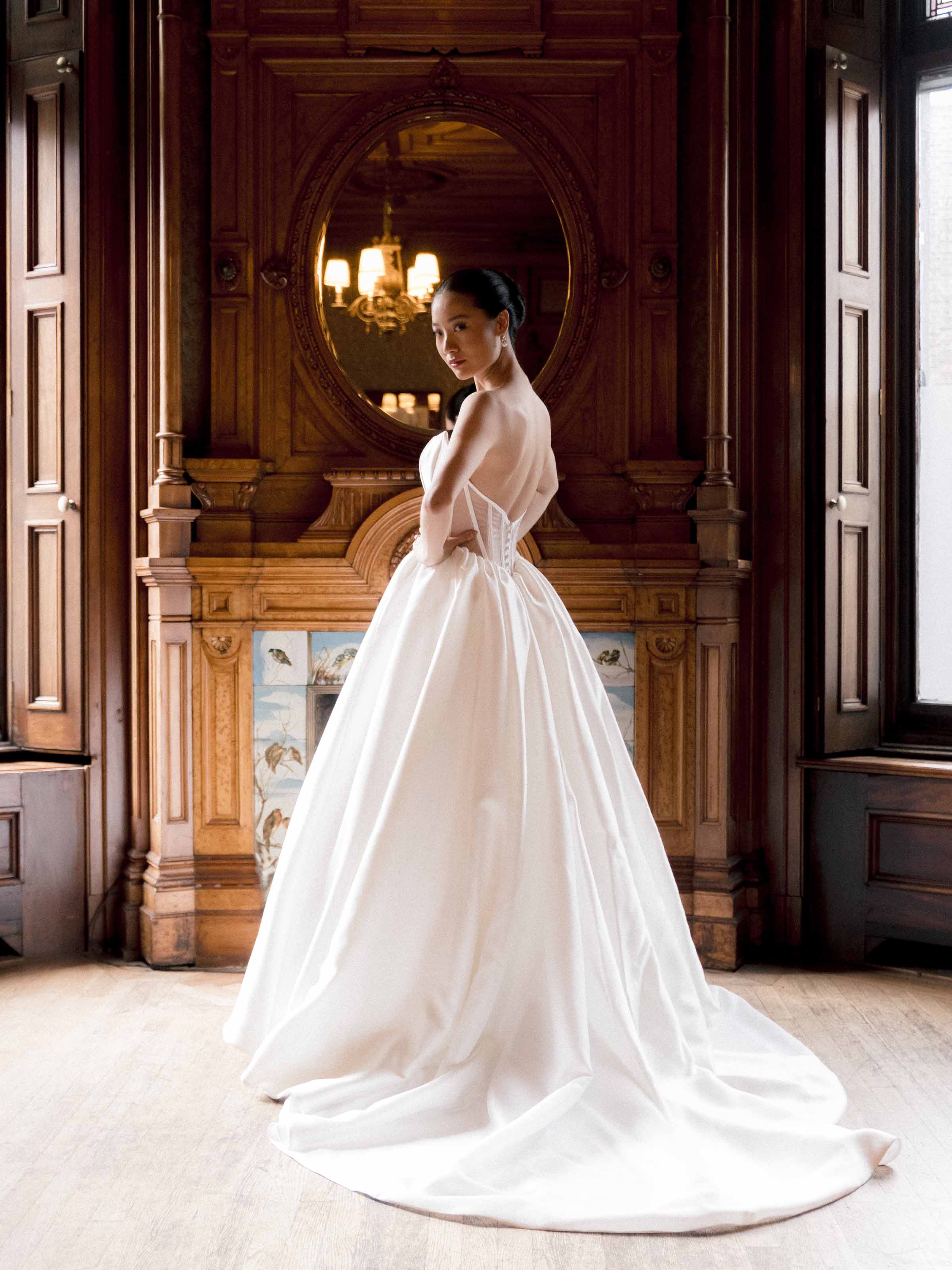 Mariée en robe de bal en satin devant un foyer en bois sculpté, Montréal