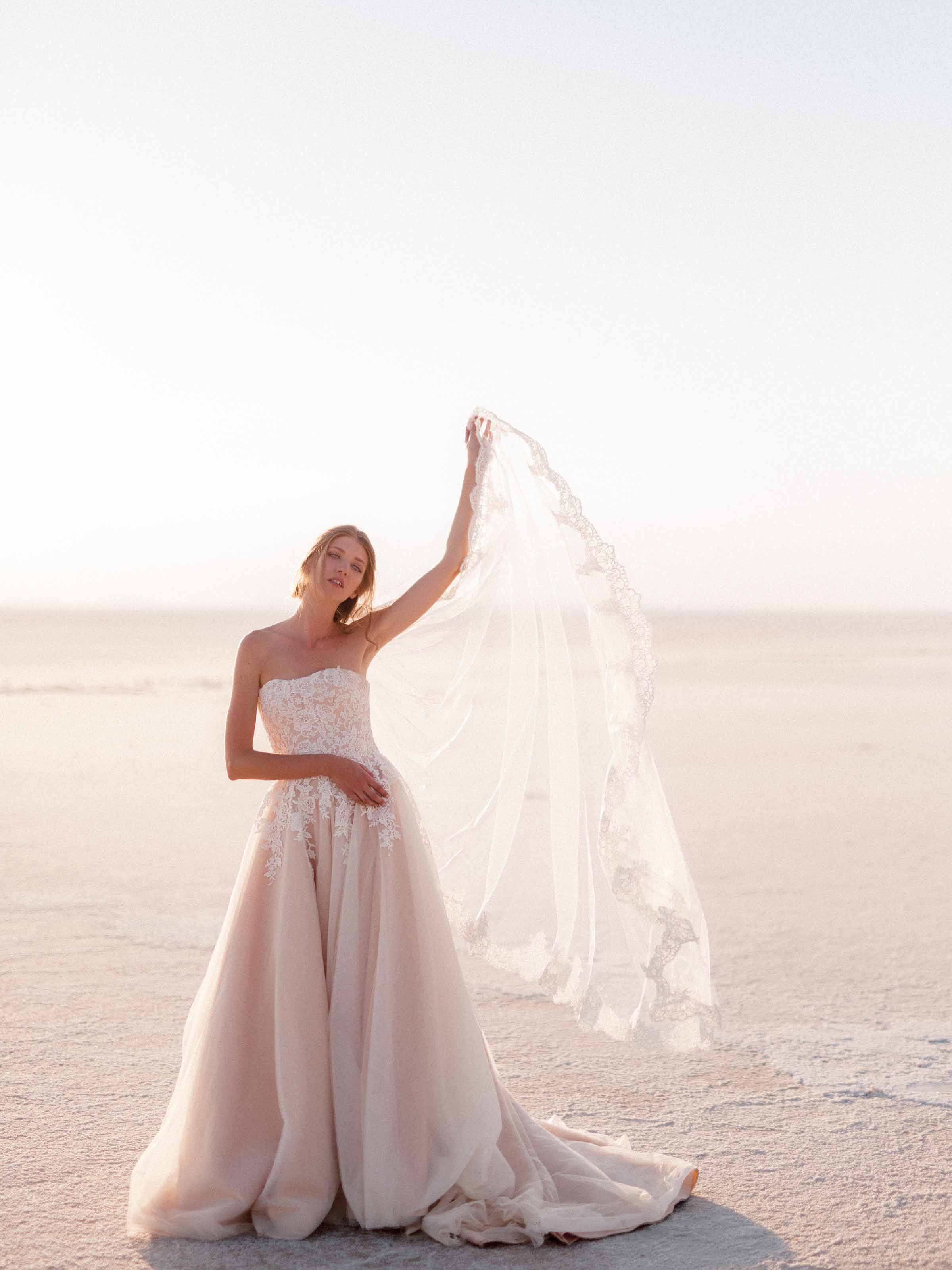 Bride holding her lace veil out in the wind on the salt flats of Tuz Gölü, Türkiye