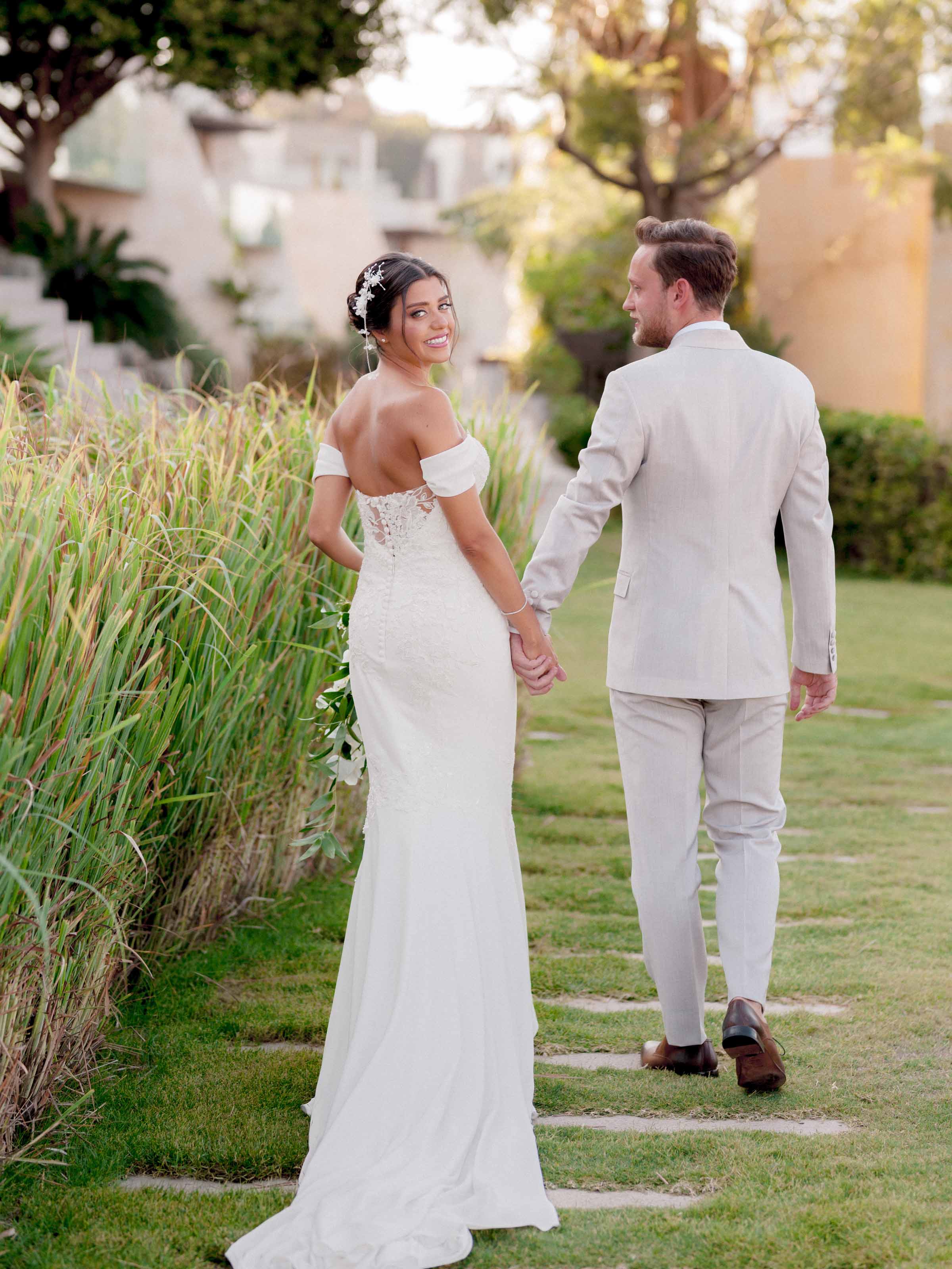 Couple walking hand in hand past tall reeds, Kuum, Bodrum