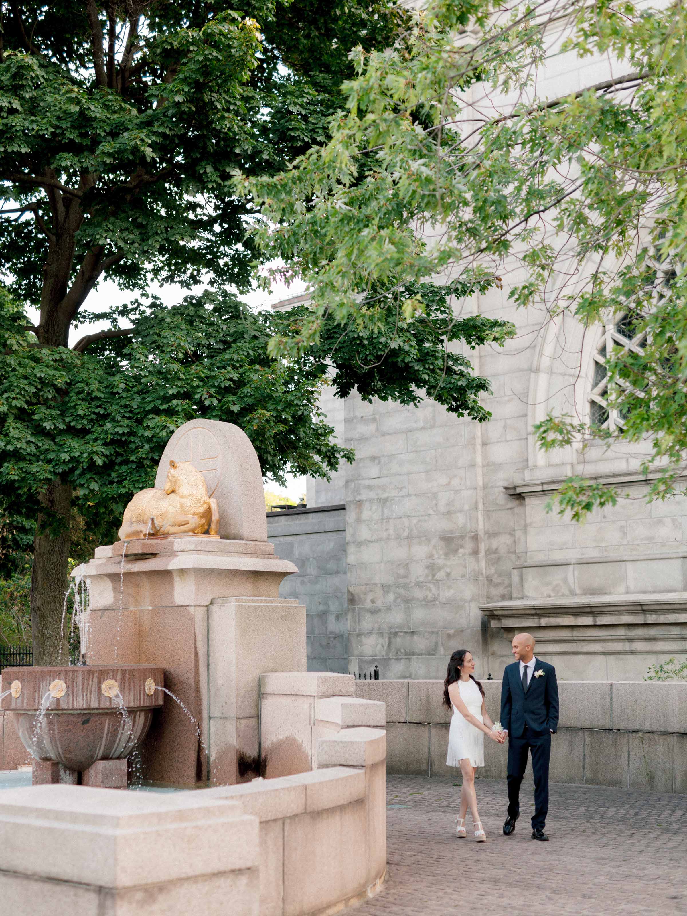 Couple standing beside a stone fountain outside a church, Montréal