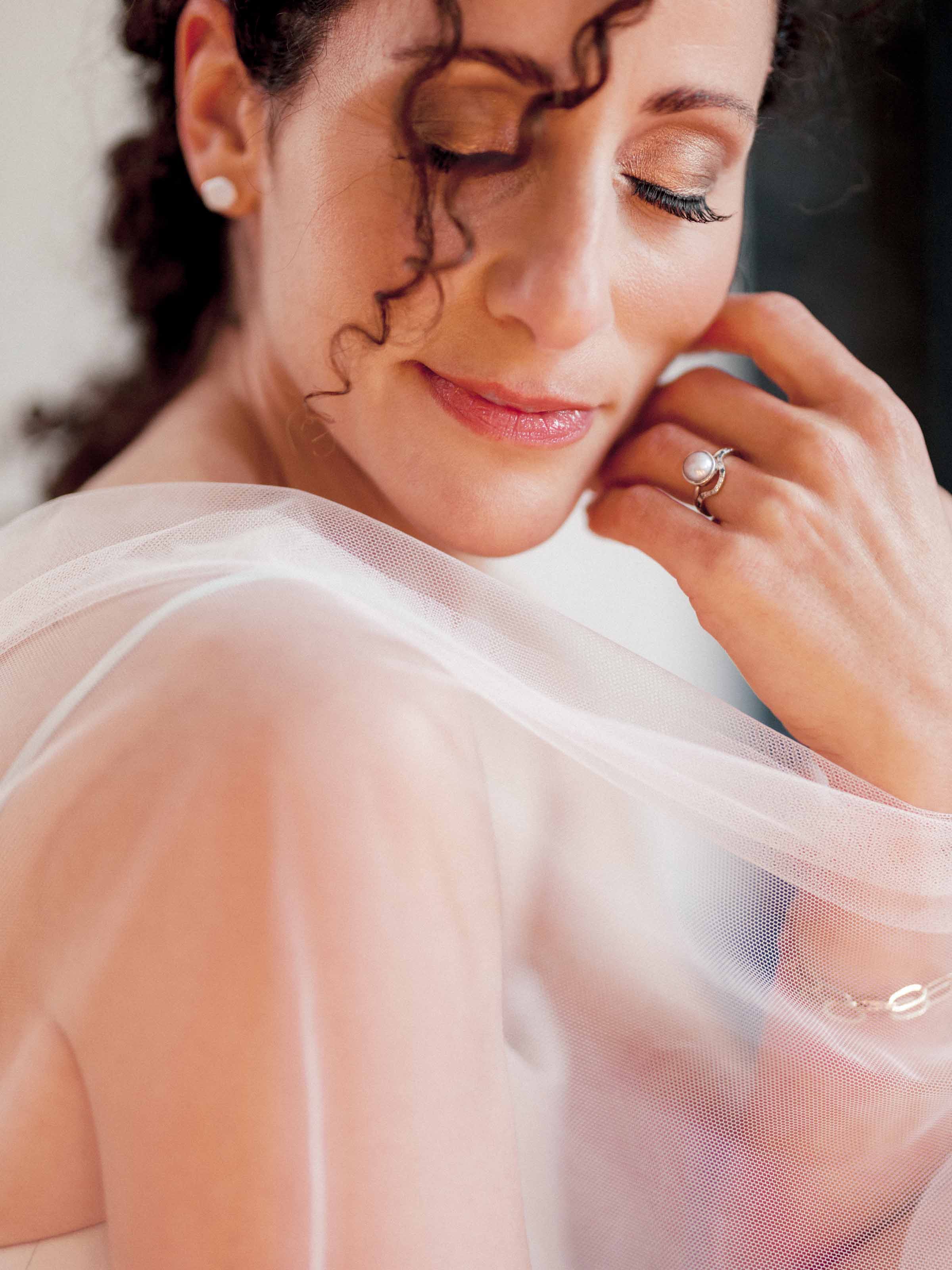 Bride in a tulle veil resting her ringed hand at her cheek, Montreal