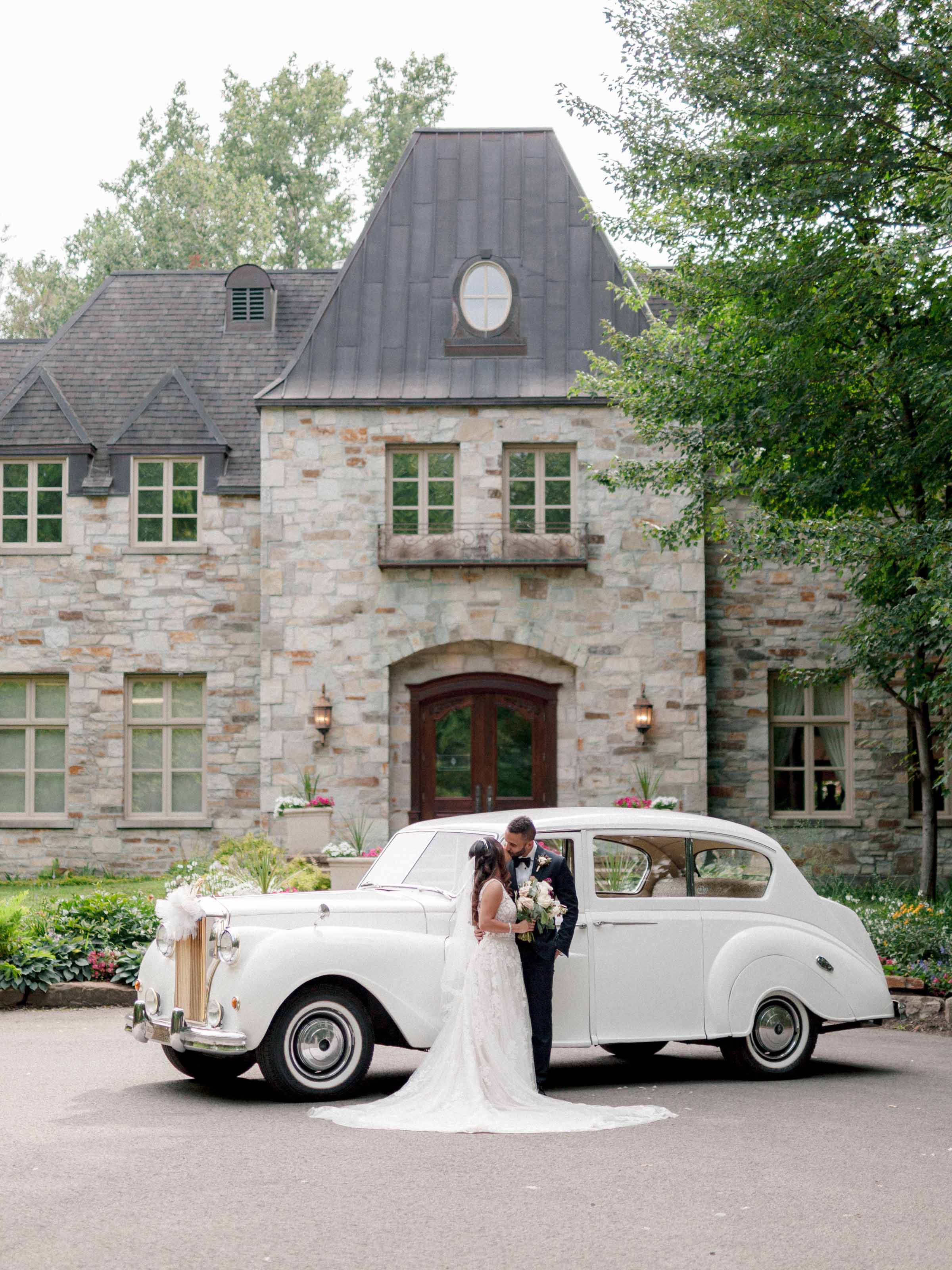 Couple beside a white vintage car outside a stone manor, Montréal