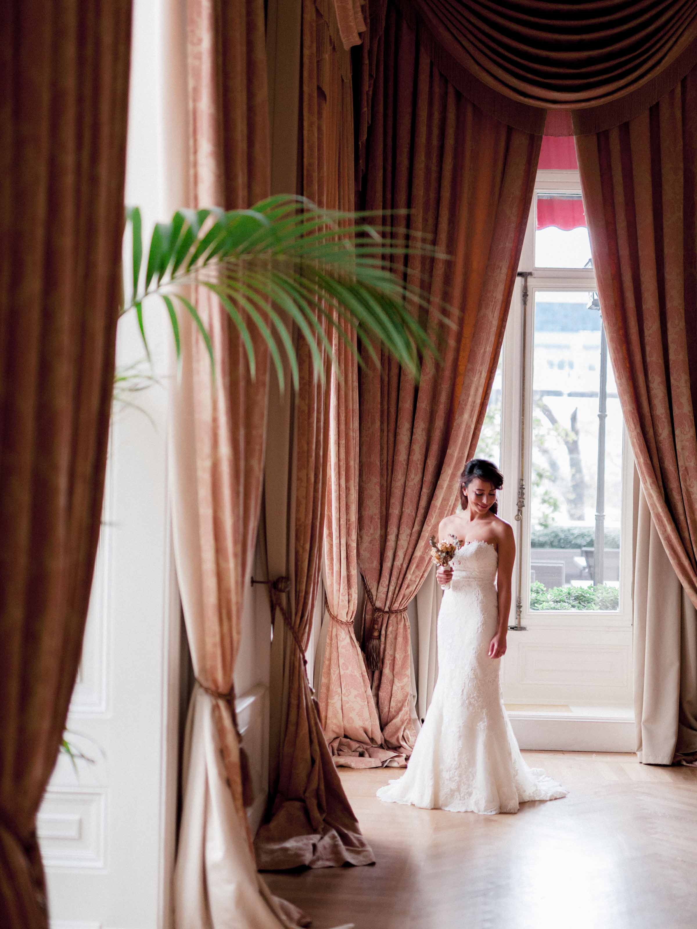 Bride framed by tall drapes and a window, Pera Palace, Istanbul