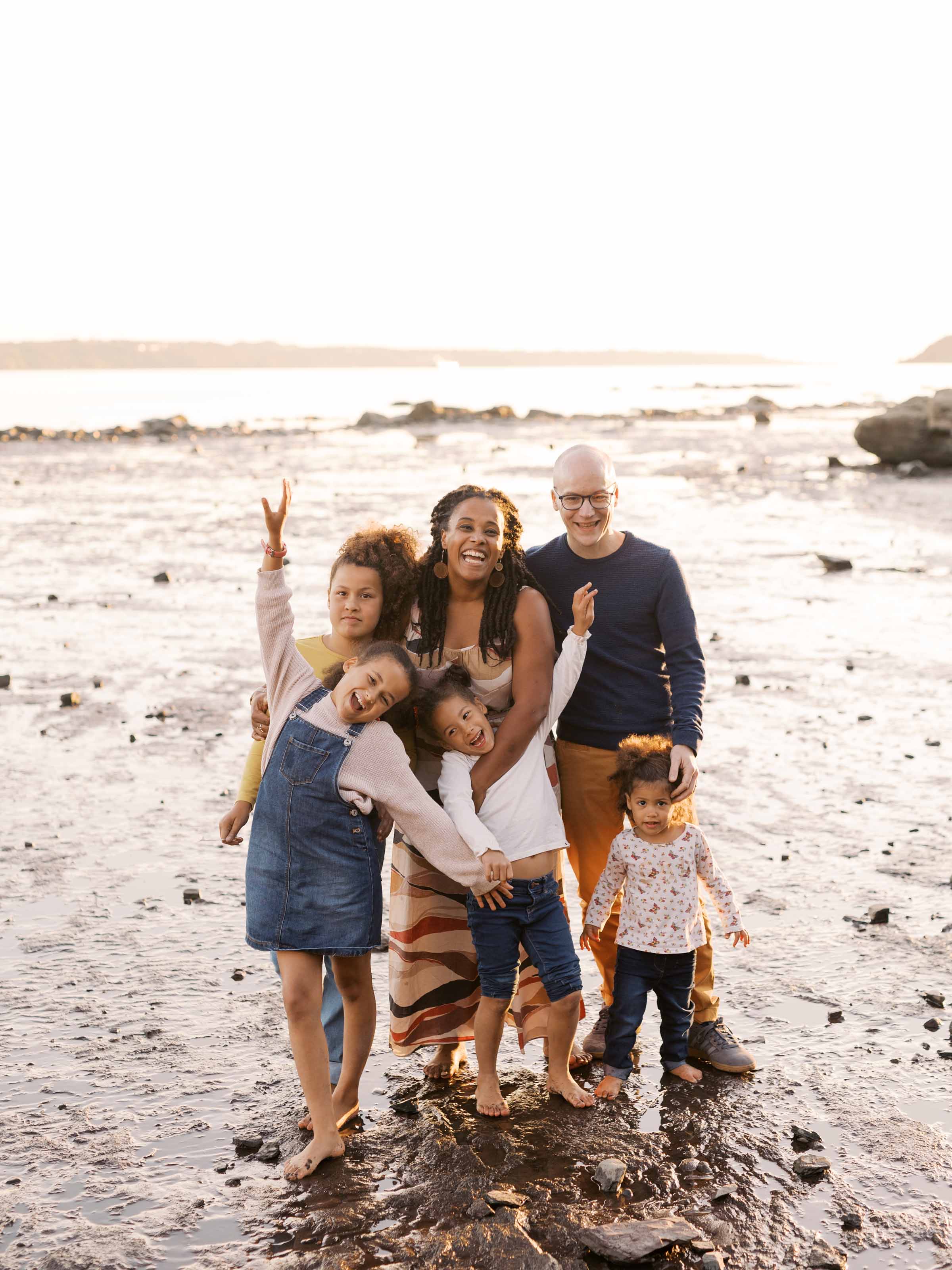 Famille de six personnes réunie sur le sable à marée basse, les enfants faisant signe de la main, ville de Québec