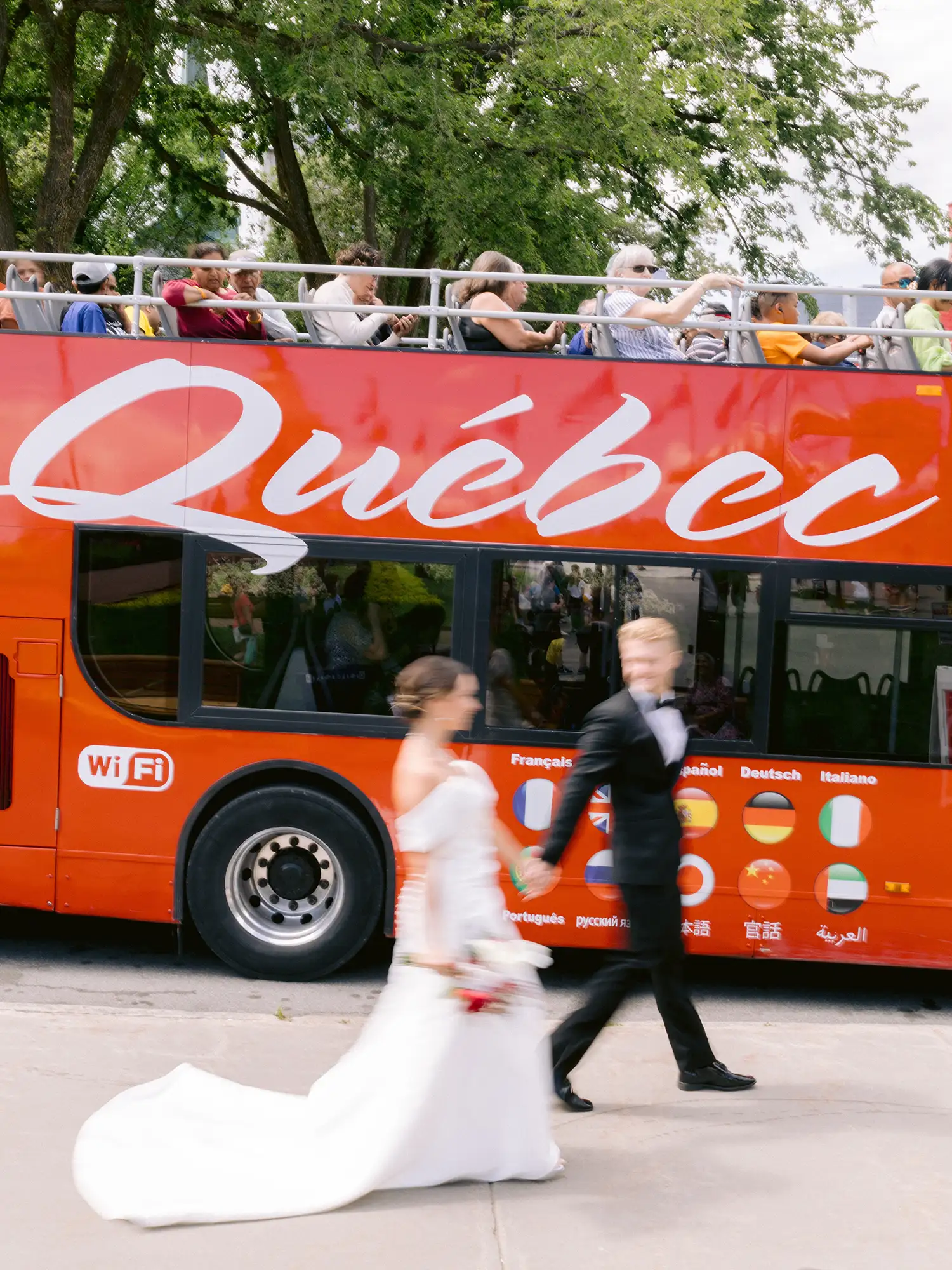 Bride and groom walking past a red tour bus in Old Quebec on their elopement day