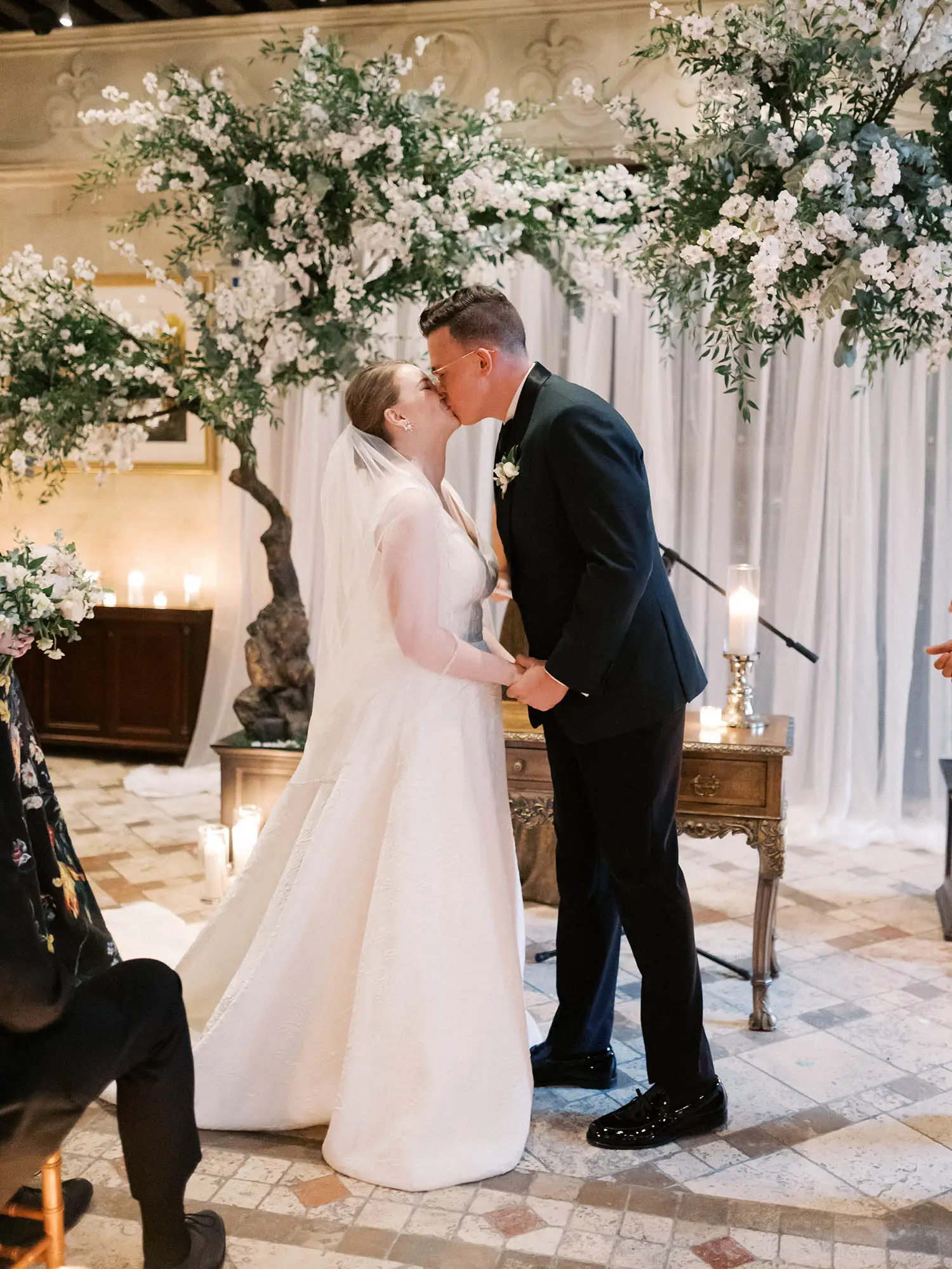Couple kissing at the end of their ceremony beneath flowering branches in Quebec City