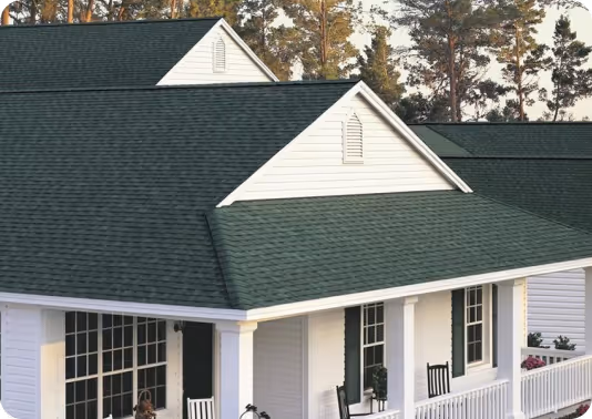 White houses with dark green shingle roofs surrounded by trees.