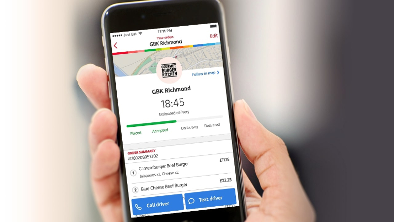 Hand holding phone showing order tracking for GBK Richmond with estimated delivery time and call or text driver options.