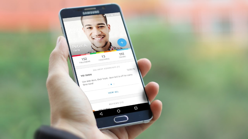 Hand holding Samsung smartphone displaying a social media profile with followers and orders stats.