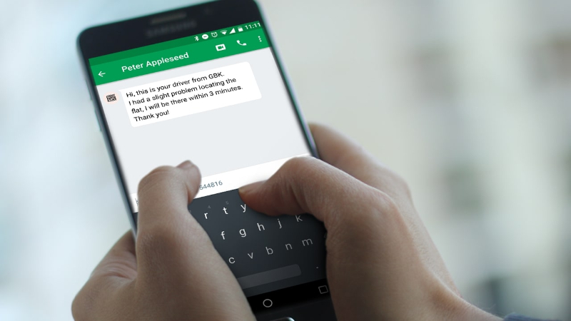 Person typing on smartphone showing a message from Peter Appleseed about driver location delay.