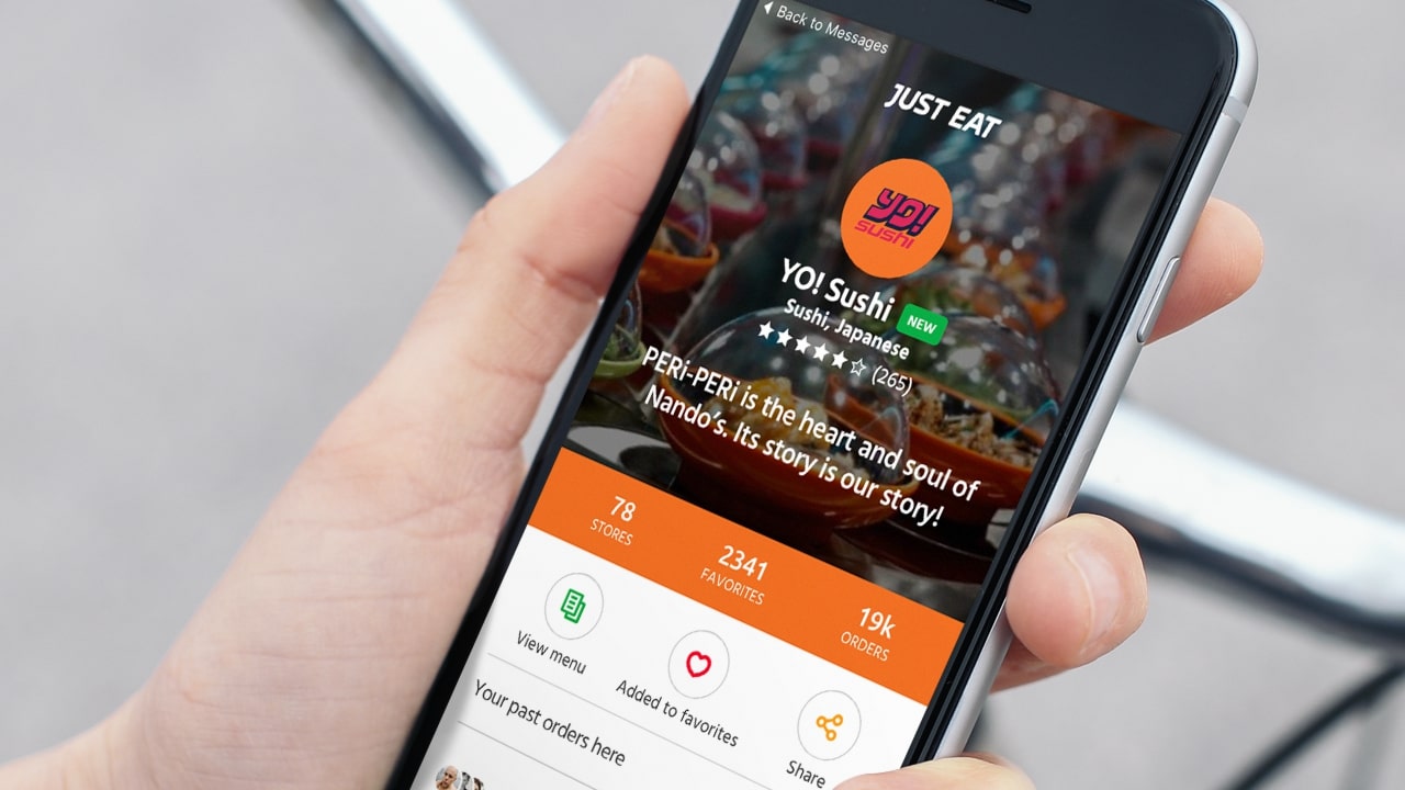 Hand holding phone displaying Just Eat app with Yo! Sushi restaurant page and ratings.