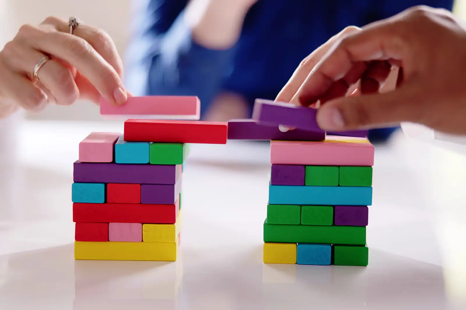 Pessoas montando uma "ponte" com blocos de madeira coloridos.