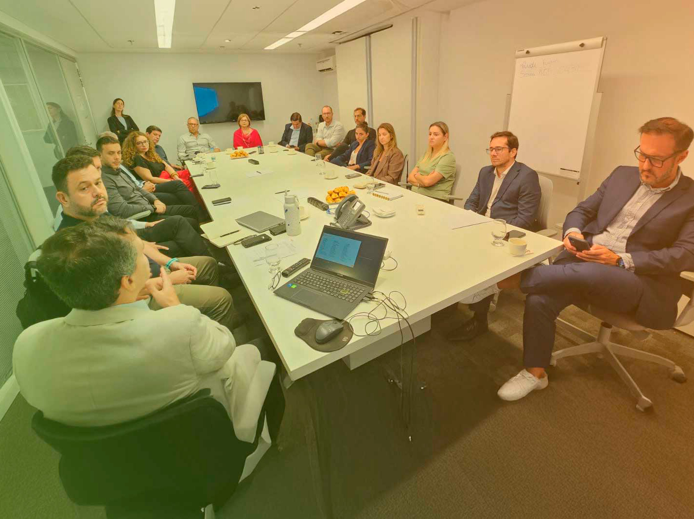 pessoas sentadas ao redor de uma mesa em uma sala de reunião