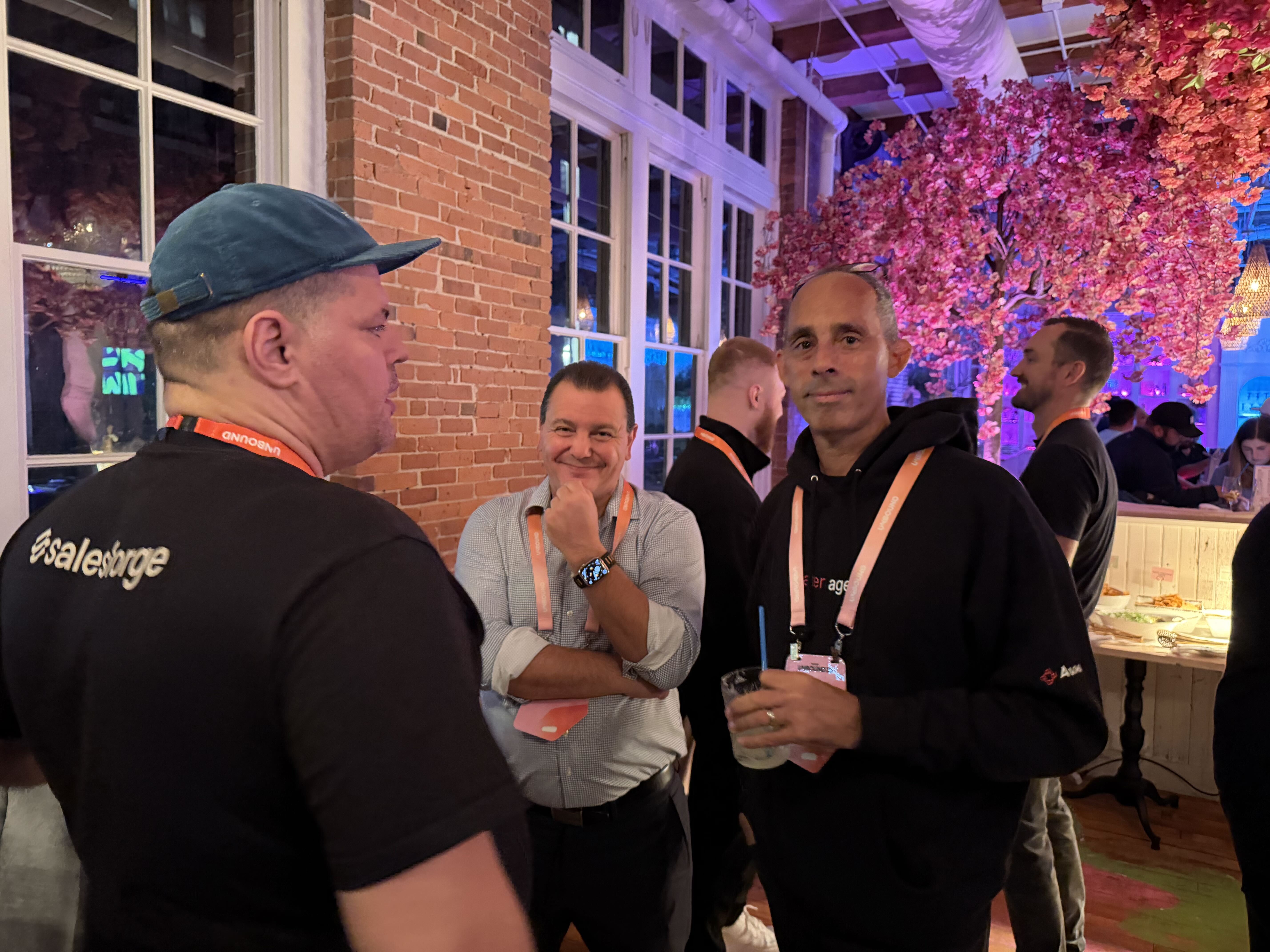 Avoma team members talking with GTM leaders under the pink flower installation at the UNBOUND dinner