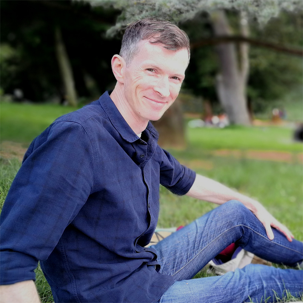 Man sitting on grass in a park.