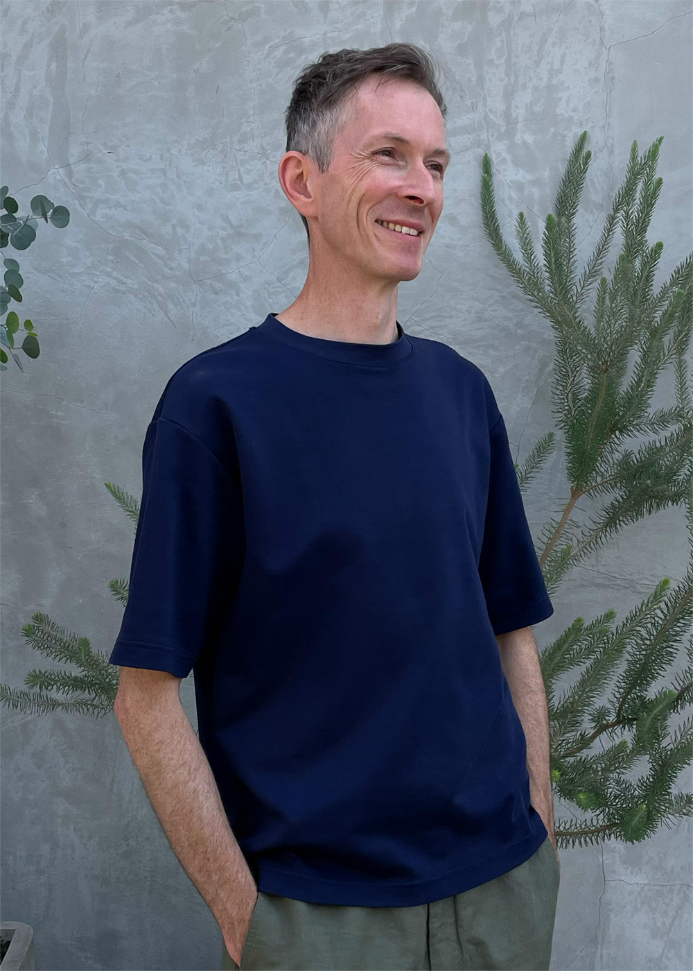 Matt Ainsley stood against a concrete wall with plants in Tokyo