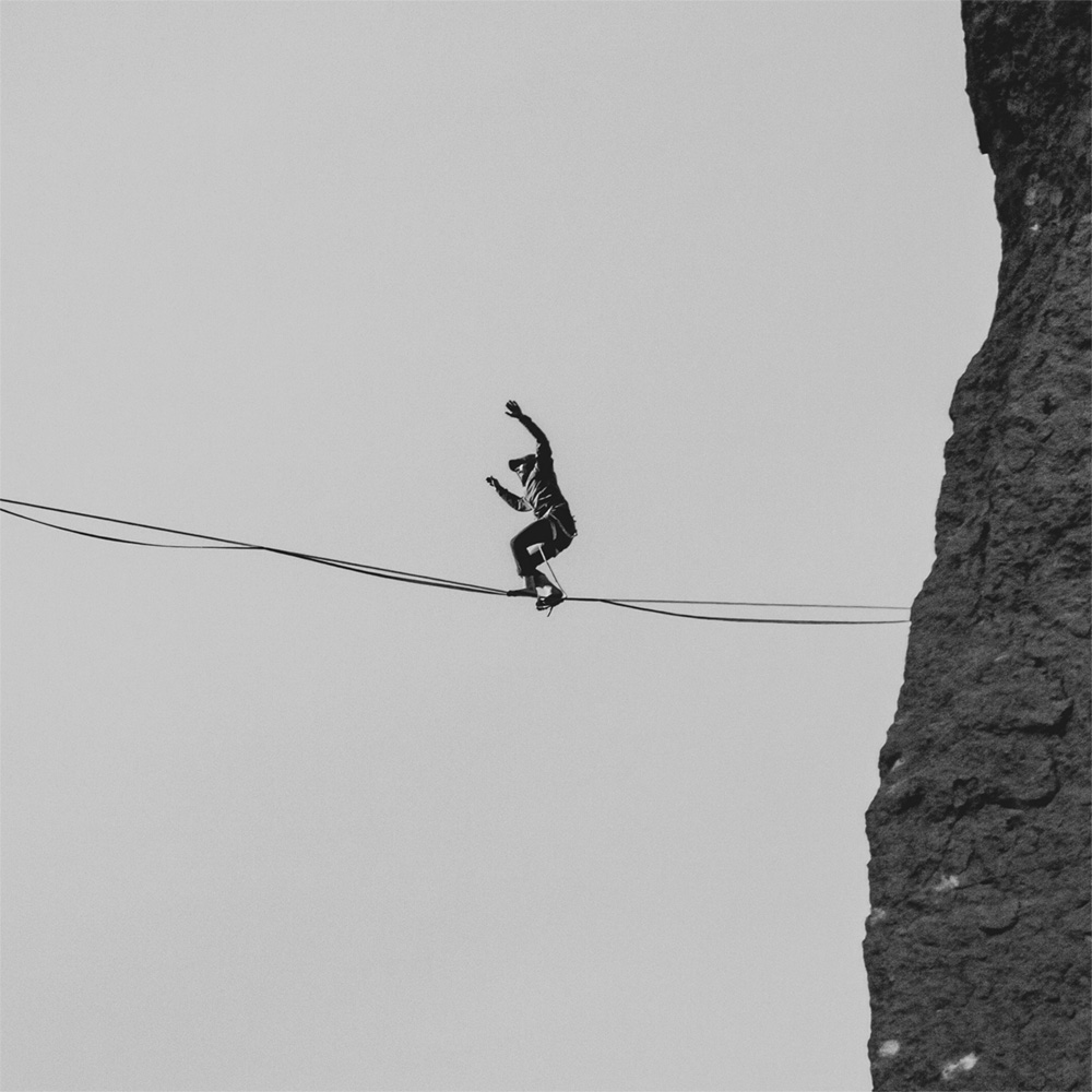 Black and white photo of man tightrope walking