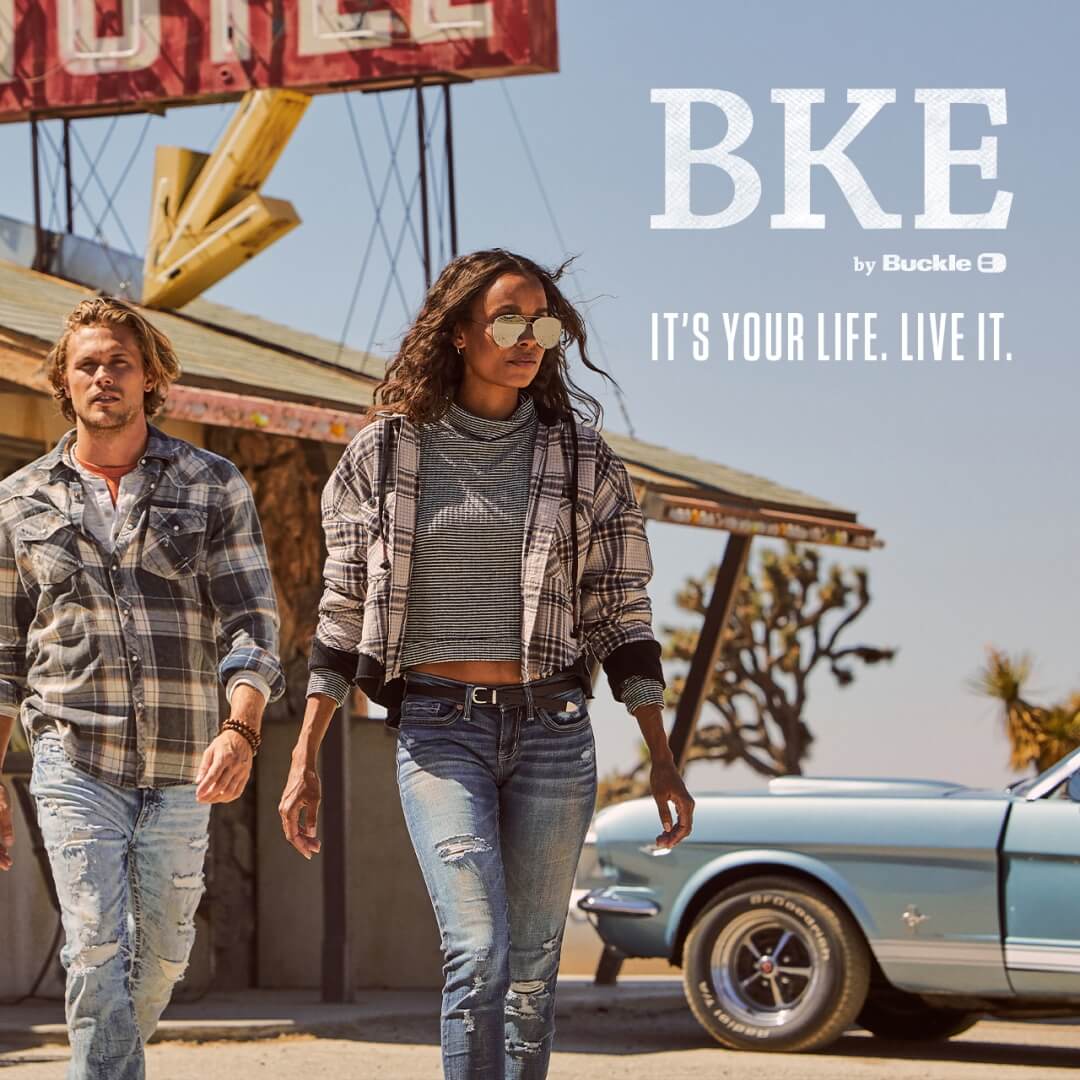 Photo of a young man and woman wearing Buckle clothes outside an old-fashioned hotel