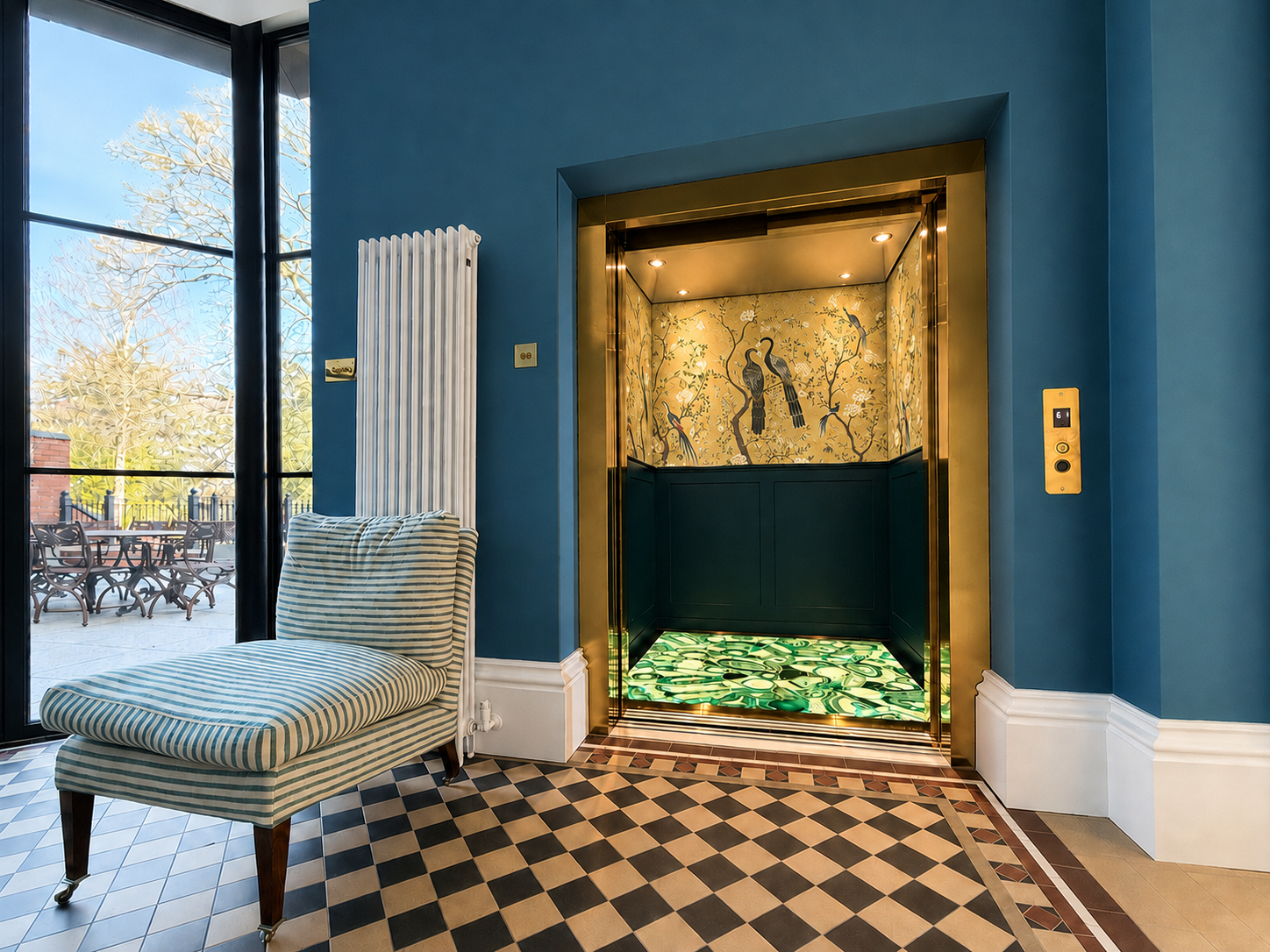 Open home lift with gold trim, floral bird wallpaper, and patterned floor in blue walled room.