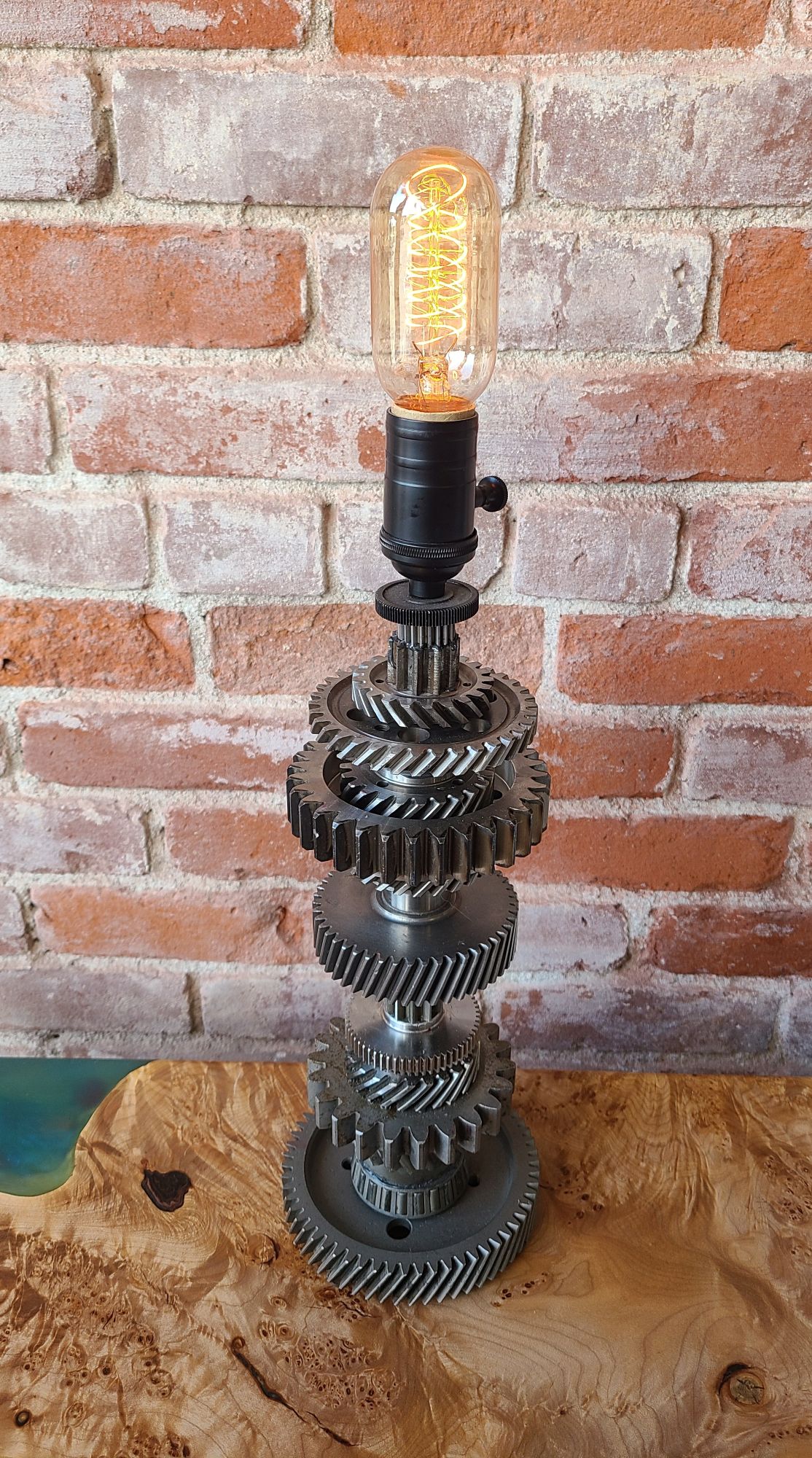 Lamp made of misc. vintage gears, with built-in dimmer switch and 40 W Edison loop bulb. 16" high without bulb. 54" grey twisted cloth plug.