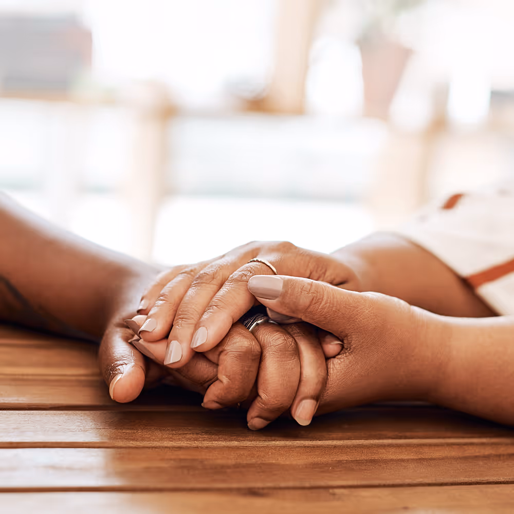 Closeup of a couple’s hands lovingly holding each other.