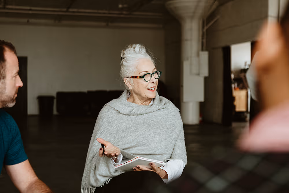 A group therapy session for veterans. An older female therapist is speaking to the group about the challenges and rewards of addiction recovery for veterans.