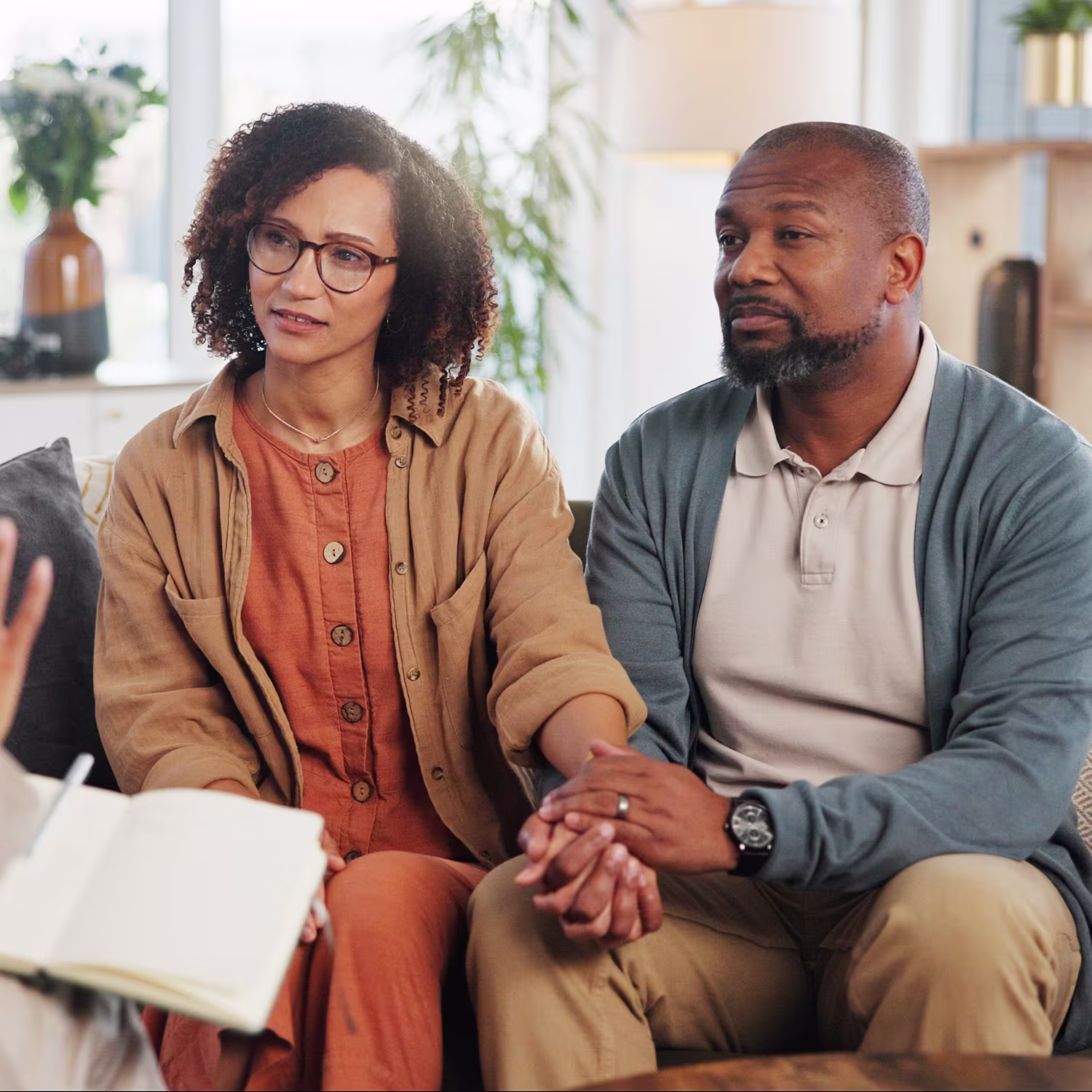A couple sits together in a therapist’s office, listening with concern and support