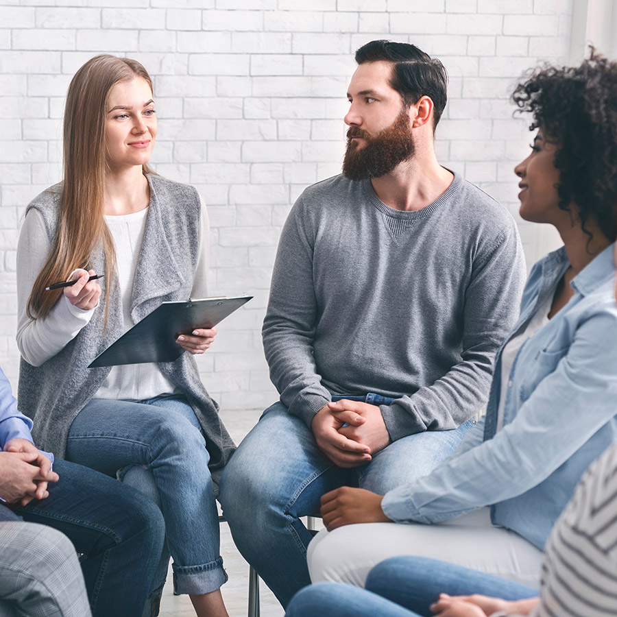 A psychologist talking to a diverse group of people seeking addiction support services.