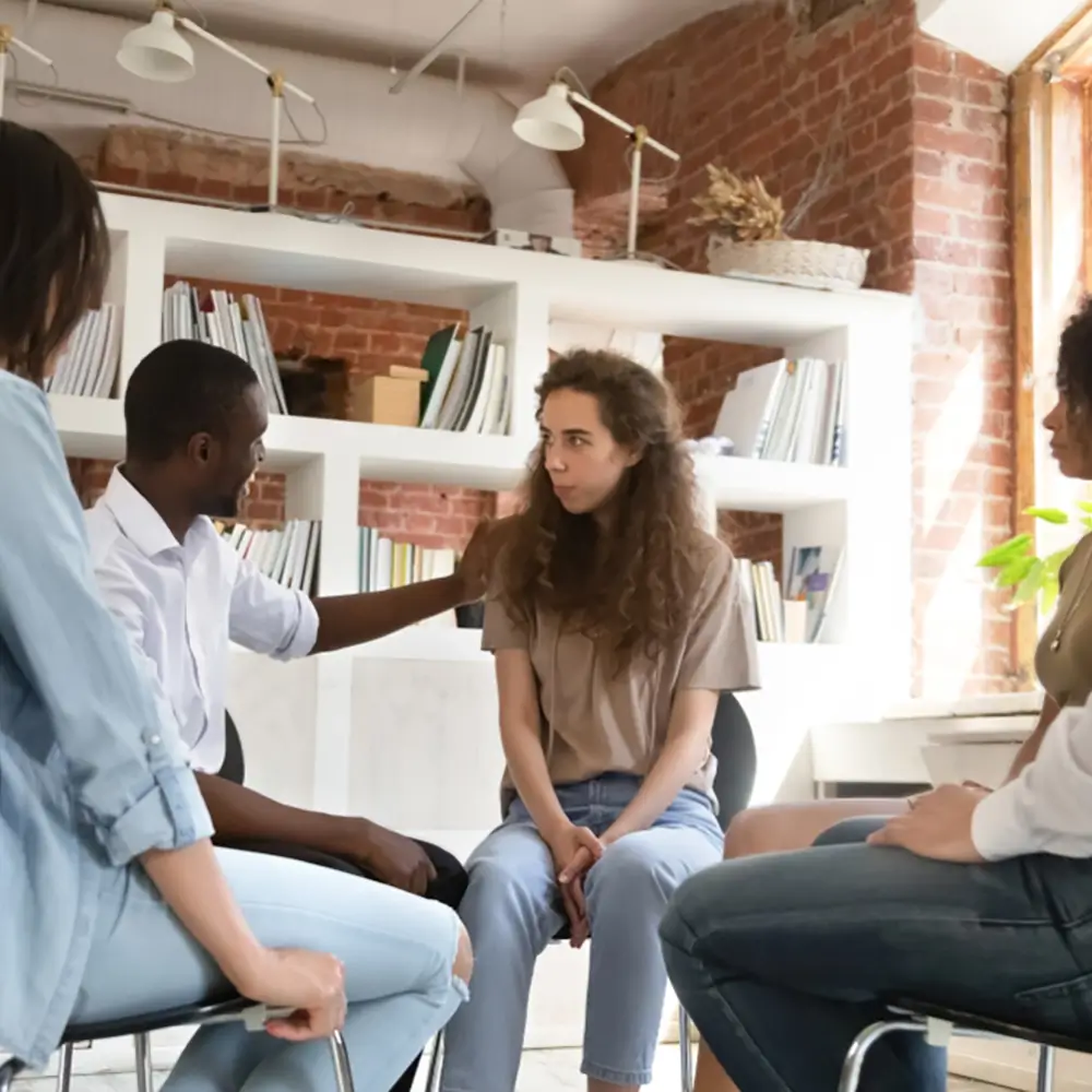 Supportive group therapy session at a medical detox centre, where diverse clients share their experiences and a psychologist gently encourages a new participant