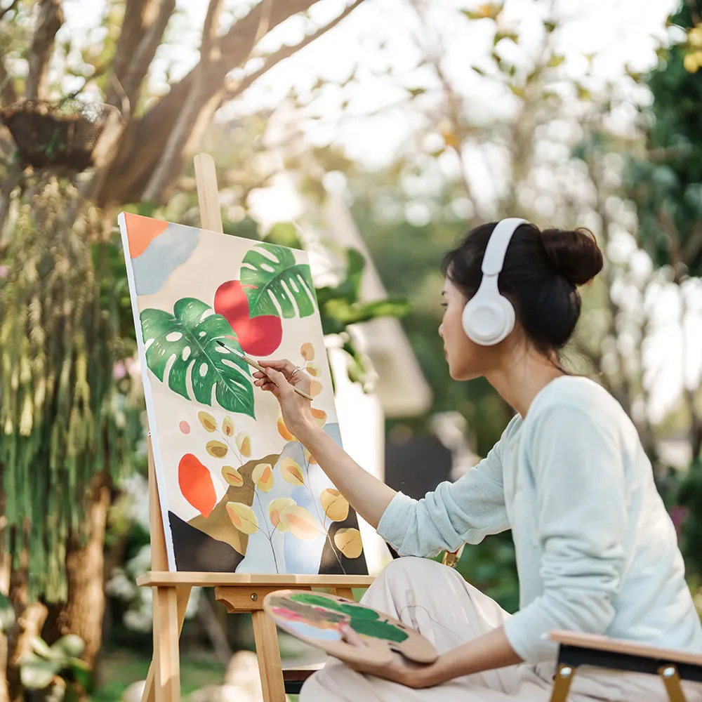 A resident in one of our creative rehab programs, sitting in the garden and painting floral art.