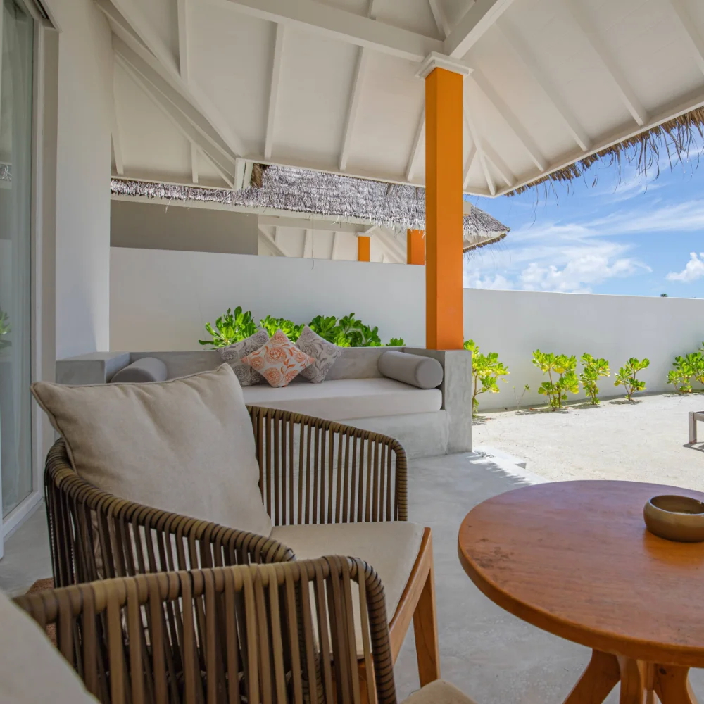 View from a private luxury residence looking out onto a sandy backyard and beachfront, with loungers and tropical landscaping designed for peaceful, discreet recovery.