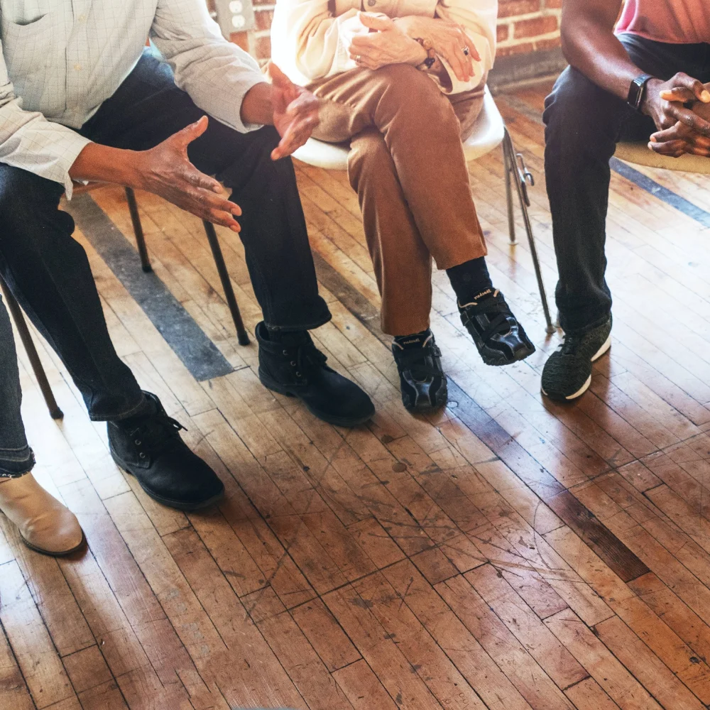 Close-up of a supportive therapy circle, with hands and gestures reflecting trust, connection, and shared healing in an outpatient recovery group.