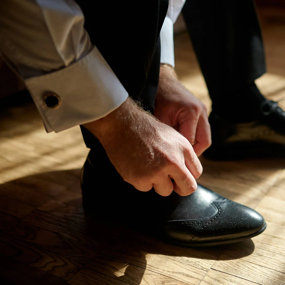 Man in transitional housing tying his shoelaces as he prepares for a new day of work, rebuilding structure and independence after inpatient rehab.