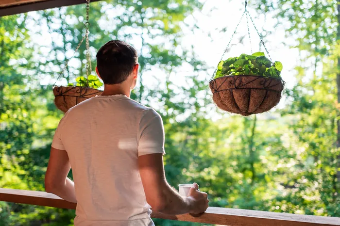 A sober former client, his back to us, enjoying tea on his porch in the early morning sunlight.
